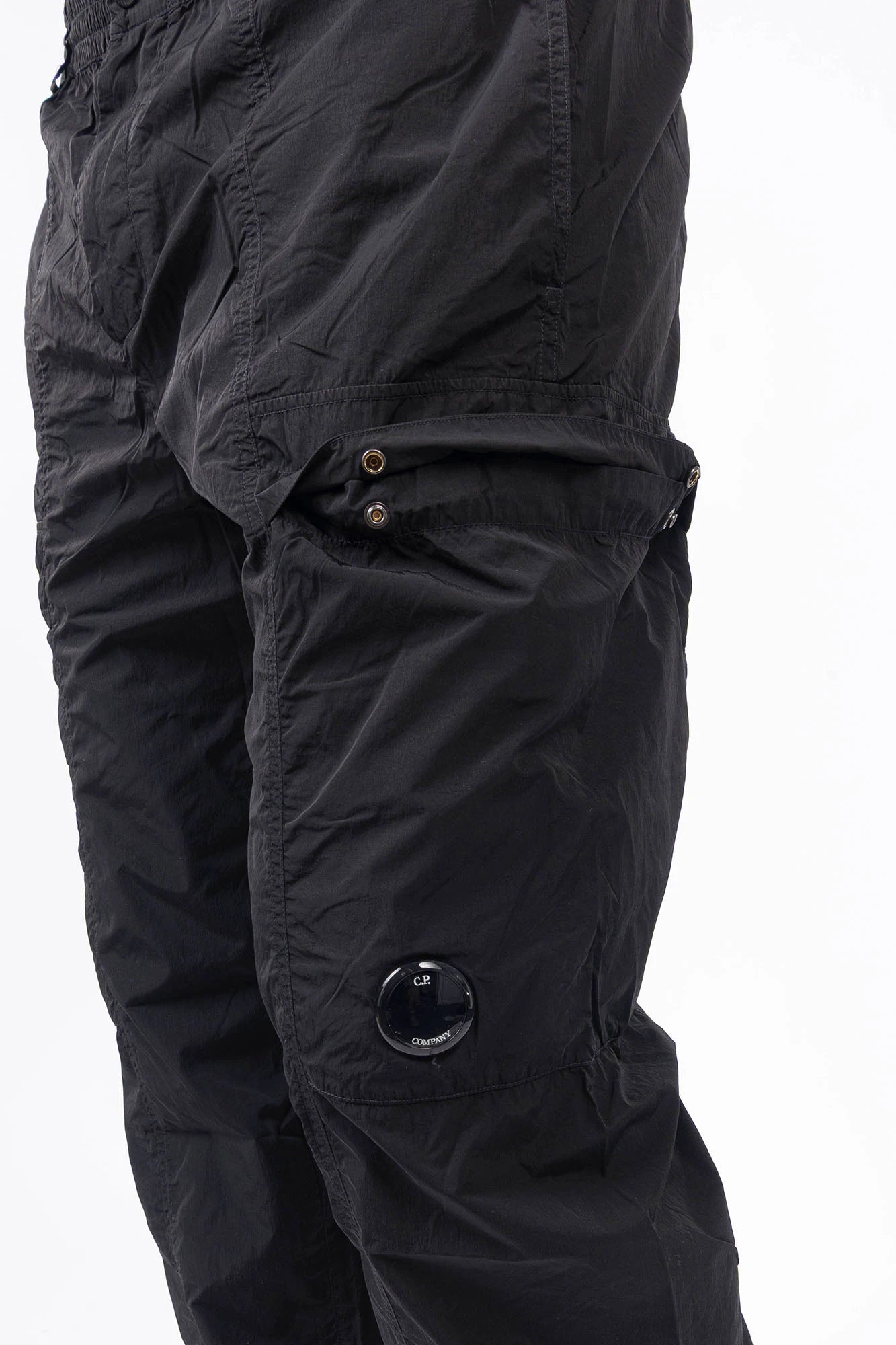 C.P. Company, Mens Pants, Black 999, Chrome-R Polyamide Nylon Trousers, Cargo Pockets, Side Pockets, Signature Lens, Lens Detail, Loose Fit, Straight Leg, Belt Loops, Zip-Fly, Button Closure, Back Pockets, British Saylor, Chester Perry, Massimo Osti, Front 3/4 Close-up View. 
