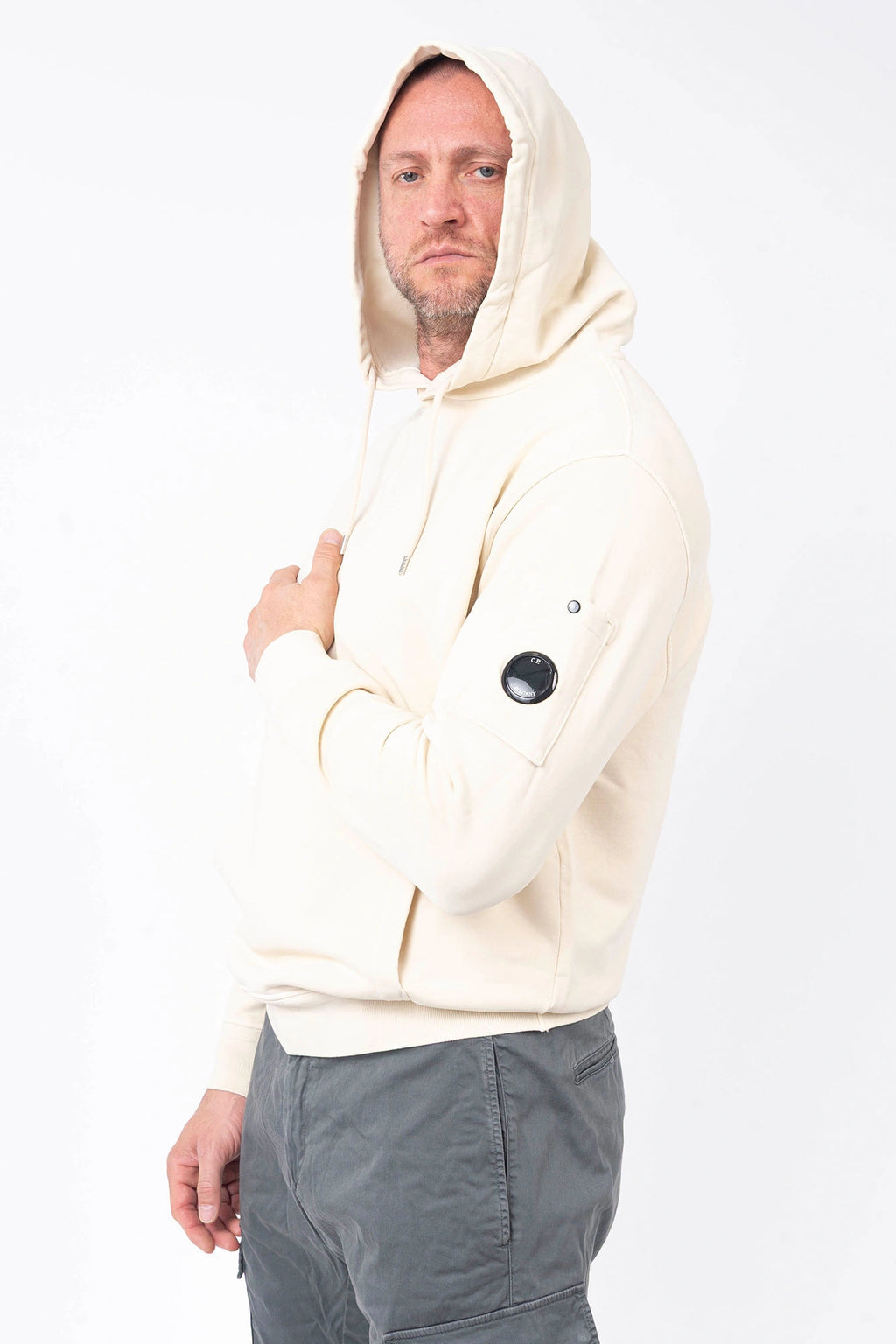 C.P. Company, Mens T-Shirt, Frozen Dew 114, White, Off-White, Ivory, Hooded, Lens Sleeve Pocket, Ribbed Hem, Ribbed Cuffs, Kangaroo Pocket, Drawstring Hood, Silver Tone Drawstring Details, C.P. Company Grey Cotton Cargo Pants, Massimo Osti, Chester Perry, British Saylor, Front 3/4 Portrait. 
