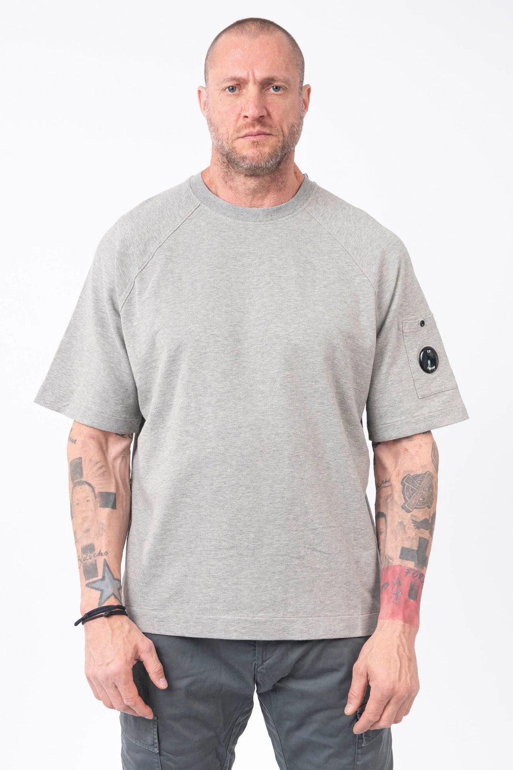 C.P. Company, Mens T-Shirt, Greystone Melange M94, Grey, Gray, Raglan Sleeves, Lens Sleeve Pocket, C.P. Company Signature Lens Detail, Cotton Fleece, Ribbed Hems and Neck, Tattoos, Massimo Osti, Chester Perry, C.P. Company Grey Cotton Cargo Pants, Front Portrait. 