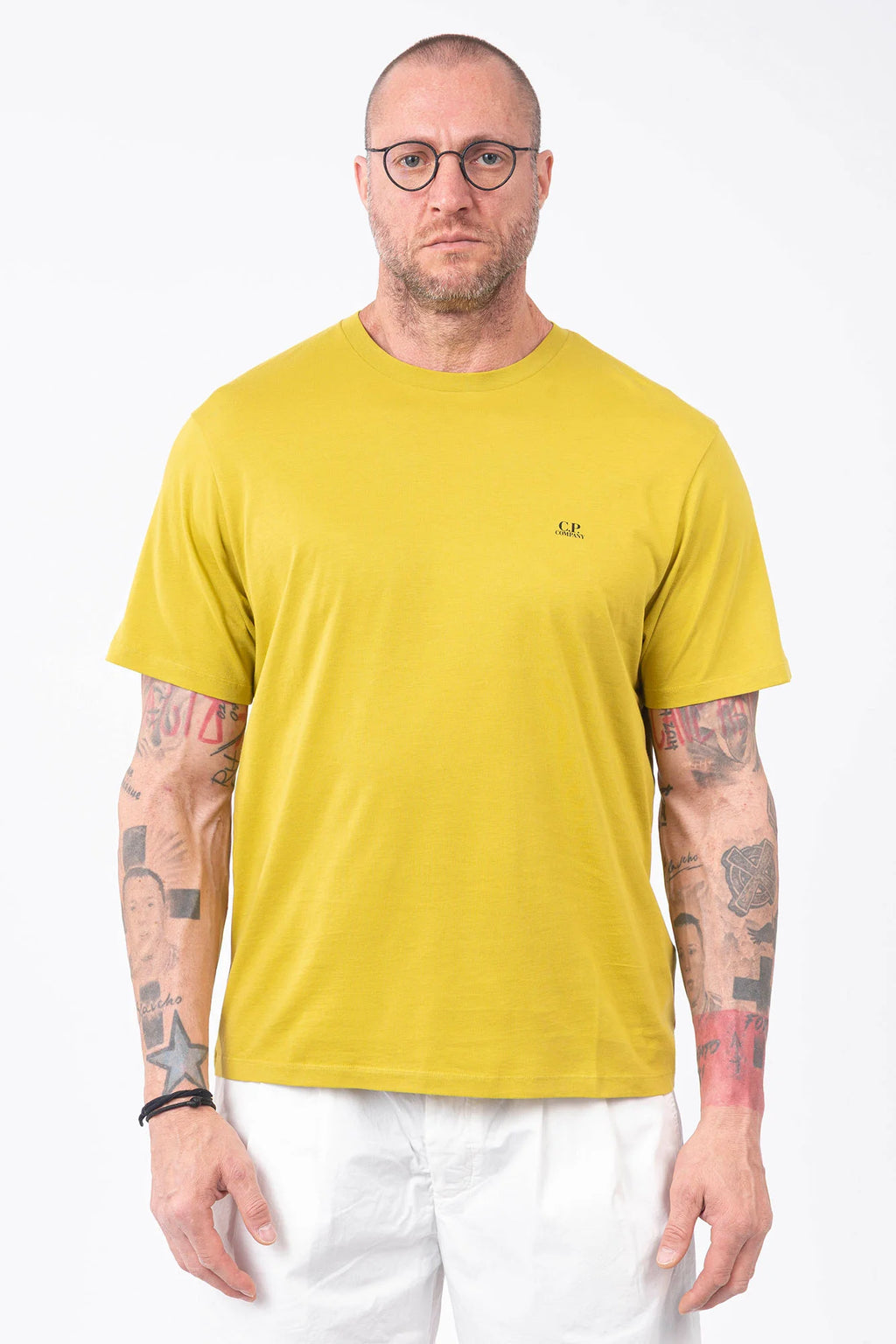 CP Company, Mens T-Shirt, Antique Moss, Yellow, Garment Dyed, Chest Logo Print, Back 'Goggles' Print, Short Sleeves, 100% Cotton, Ribbed Hems and Neck, Tattoos, Rigards Sunglasses, White CP Company Cotton Shorts, Front Portrait. 
