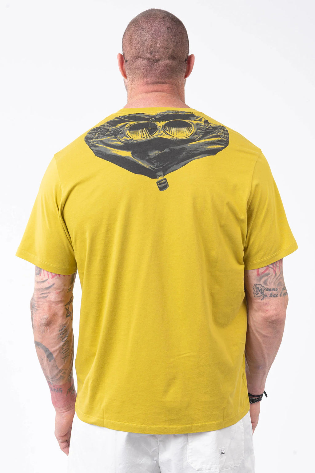 CP Company, Mens T-Shirt, Antique Moss, Yellow, Garment Dyed, Chest Logo Print, Back 'Goggles' Print, Short Sleeves, 100% Cotton, Ribbed Hems and Neck, Tattoos, Rigards Sunglasses, White CP Company Cotton Shorts, Back Portrait. 