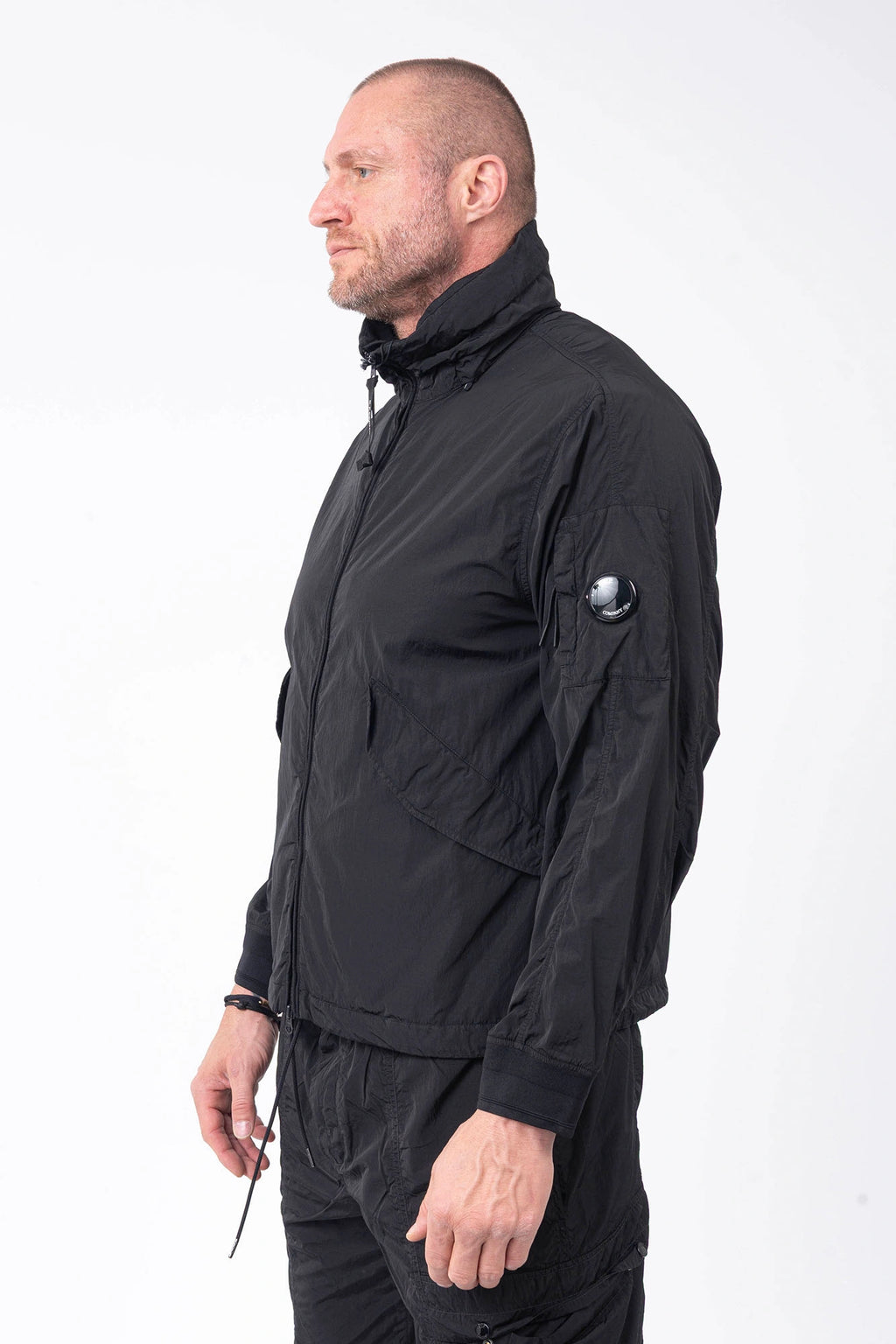 C.P. Company, Mens Jacket, Black 999, Concealed Hood, Chrome-R, Polyamide, Full-Zip, Side Flap Pockets, Sleeve Lens Pocket, Centre Zip Closure, Long Sleeves, Ribbed Elastic Cuffs, Branded Zip Puller, YKK Zippers, Two-Way Zipper, Front 3/4 View. 