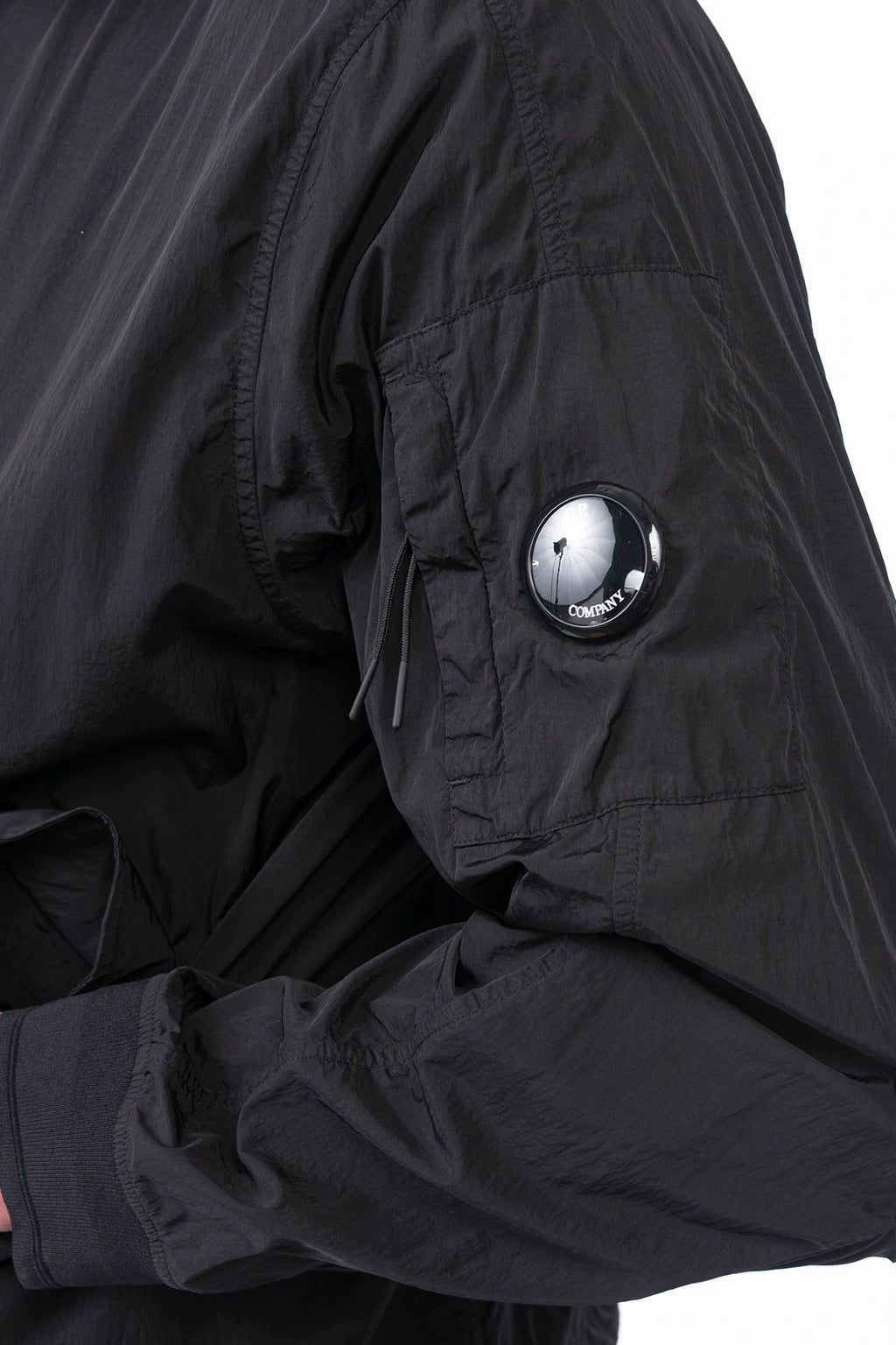 C.P. Company, Mens Jacket, Black 999, Concealed Hood, Chrome-R, Polyamide, Full-Zip, Side Flap Pockets, Sleeve Lens Pocket, Centre Zip Closure, Long Sleeves, Ribbed Elastic Cuffs, Branded Zip Puller, YKK Zippers, Two-Way Zipper, Sleeve Lens Detail Close-up. 