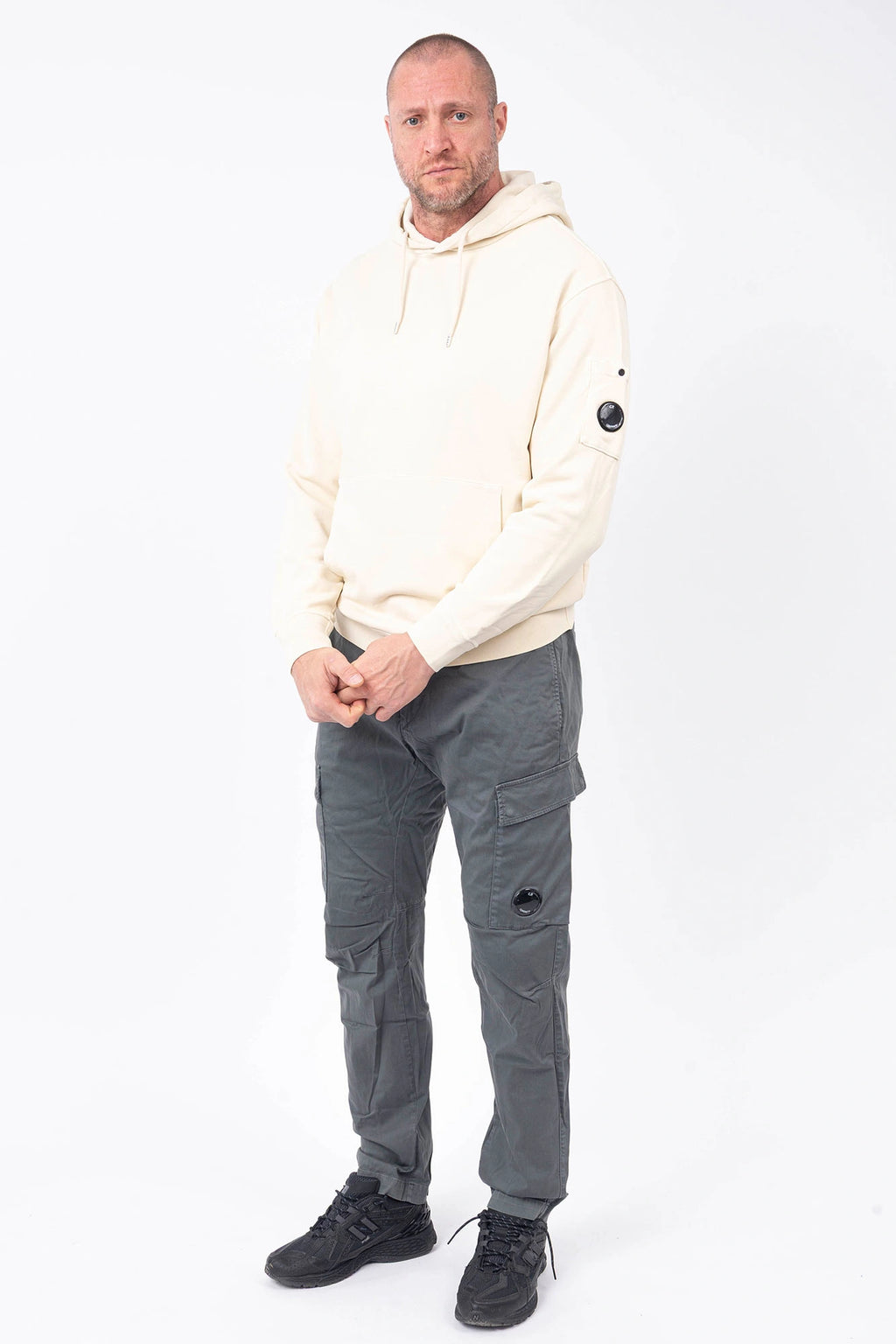 C.P. Company, Mens Pants, Gunmetal 921, Grey, Gray, Cargo Pockets, Stretch Cotton Sateen, Snap Closure Cargo Pockets, Side Pockets, Back Pockets, Belt Loops, Button Closure, Zip-Fly, Massimo Osti, Chester Perry, British Saylor, Signature Lens, Lens Pocket, Full Body Front 3/4 Portrait. 
