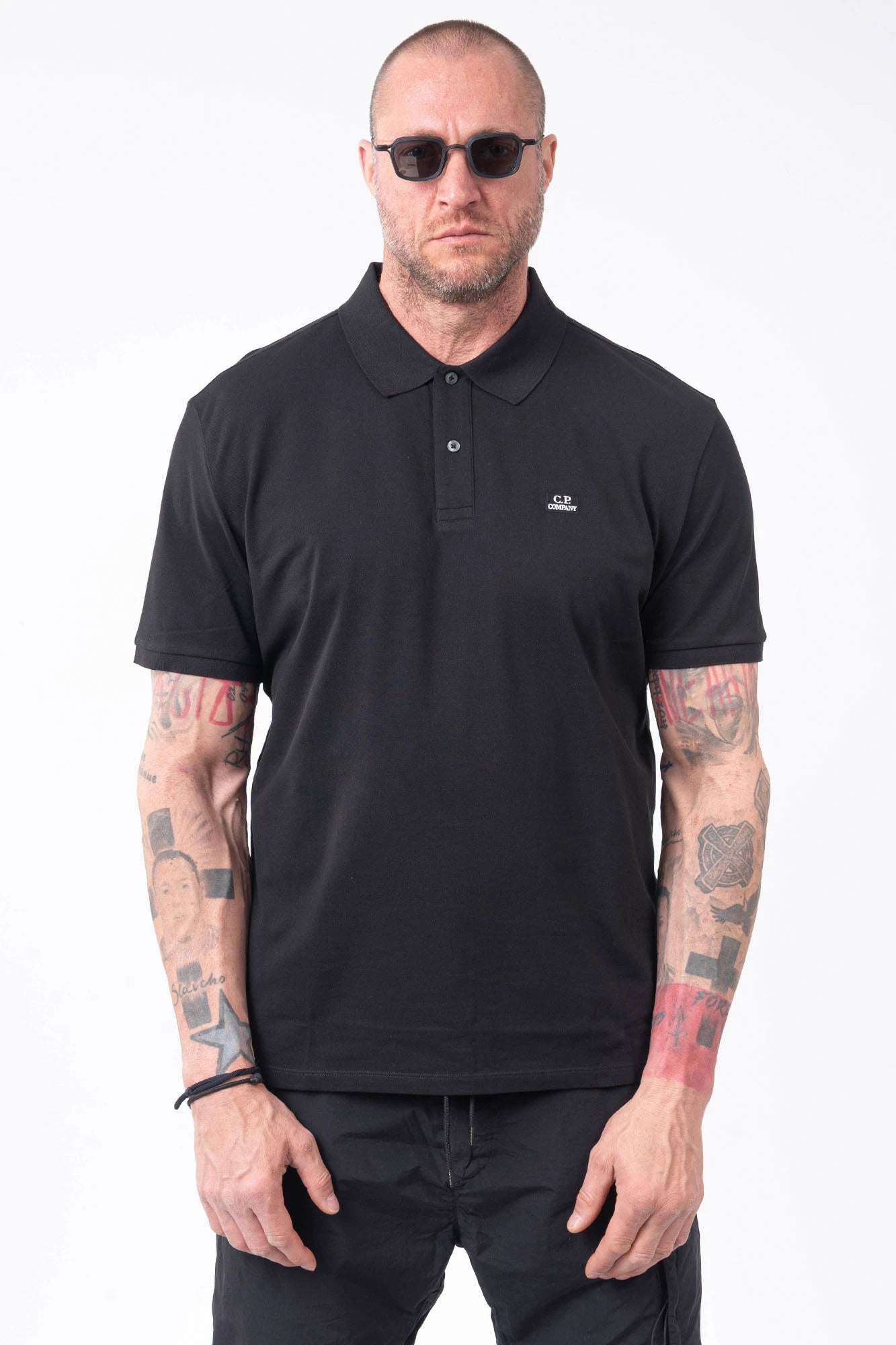 C.P. Company, Mens Polo Shirt, Black 999, Collar, Button Closure, Short Sleeves, Ribbed Hems, Stretch Cotton Pique, Chest Embroidery, Chester Perry, Massimo Osti, British Saylor, Rigards Sunglasses, Front Portrait. 