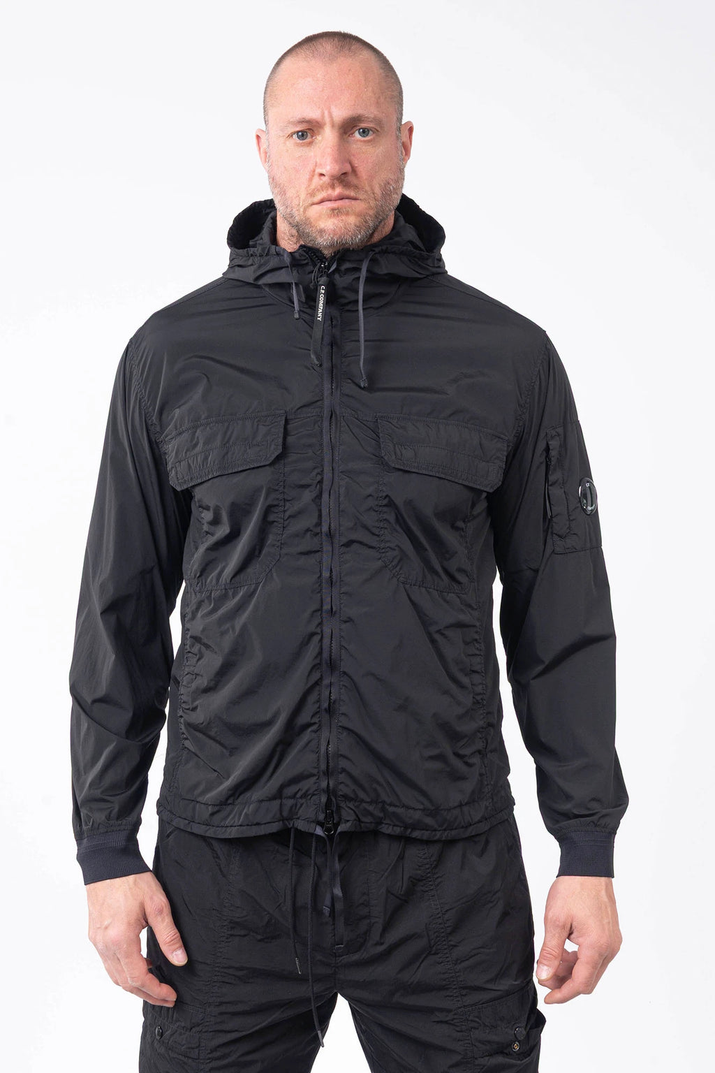 C.P. Company, Mens Jacket, Black 999, Stretch Nylon, Shell-R, Nycra-R, Hooded, Water-Resistant, Wind-Resistant, Windproof, Waterproof, Full-Zip, Centre Zip Closure, Bellow Pockets, Side Pockets, Sleeve Pocket, Massimo Osti, Chester Perry, Front Portrait. 