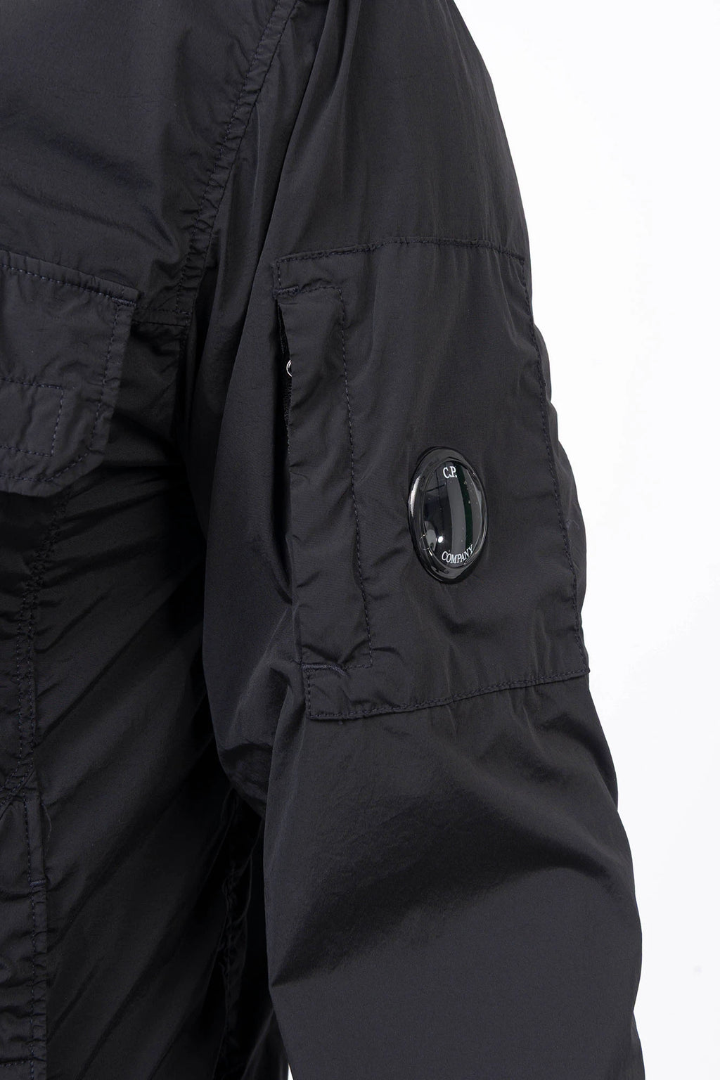 C.P. Company, Mens Jacket, Black 999, Stretch Nylon, Shell-R, Nycra-R, Hooded, Water-Resistant, Wind-Resistant, Windproof, Waterproof, Full-Zip, Centre Zip Closure, Bellow Pockets, Side Pockets, Sleeve Pocket, Massimo Osti, Chester Perry, Sleeve Accessory Close-up. 