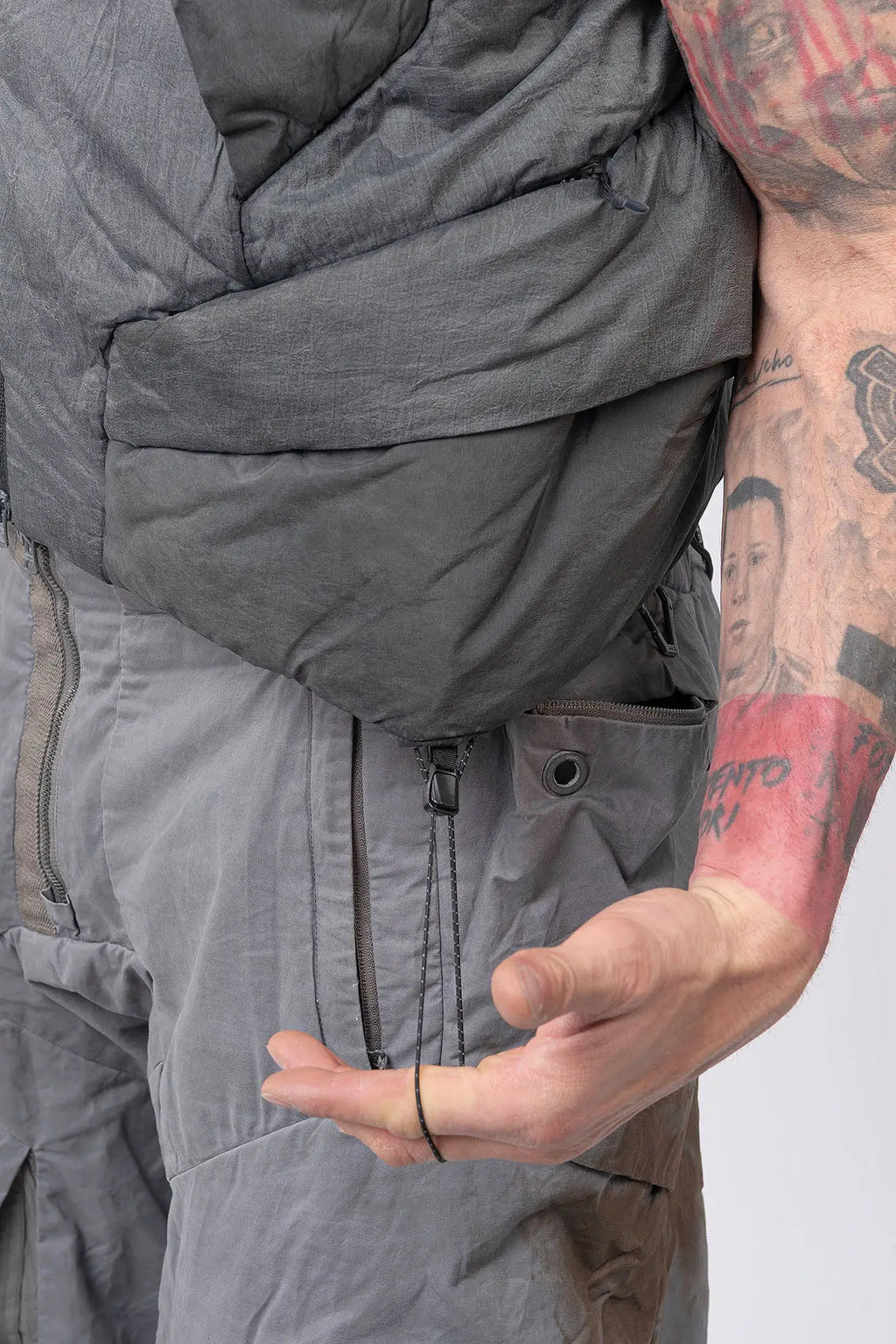 Hamcus, Mens Vest, Washed Grey, Sleeveless, Padded, Full-Zip, Multiple Zip Pockets, Breathable Design, Elastic Drawcord Adjustable Waist, Back Ventilation Cutoff, Centre Zip Closure, Full Zip, Garment Dyed, Insulated, Panel Construction, Waist Drawcord Adjuster Close-up. 