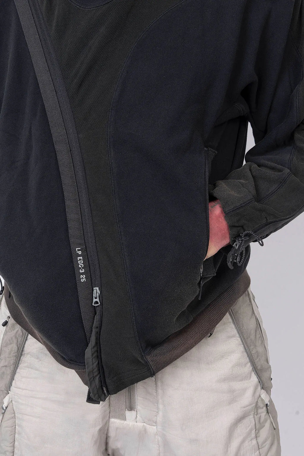 Hamcus, Mens Pullover, Black, Olive Green, Dual Long Zippers, Hybrid Garment, Convertible Garment, Long Sleeves, Adjustable Drawcord Cuffs, Ribbed Cuffs and Hem, Ventilation Design, Breathable, Modular, Multi-Functional, Hand in Pocket Front Close-up View. 