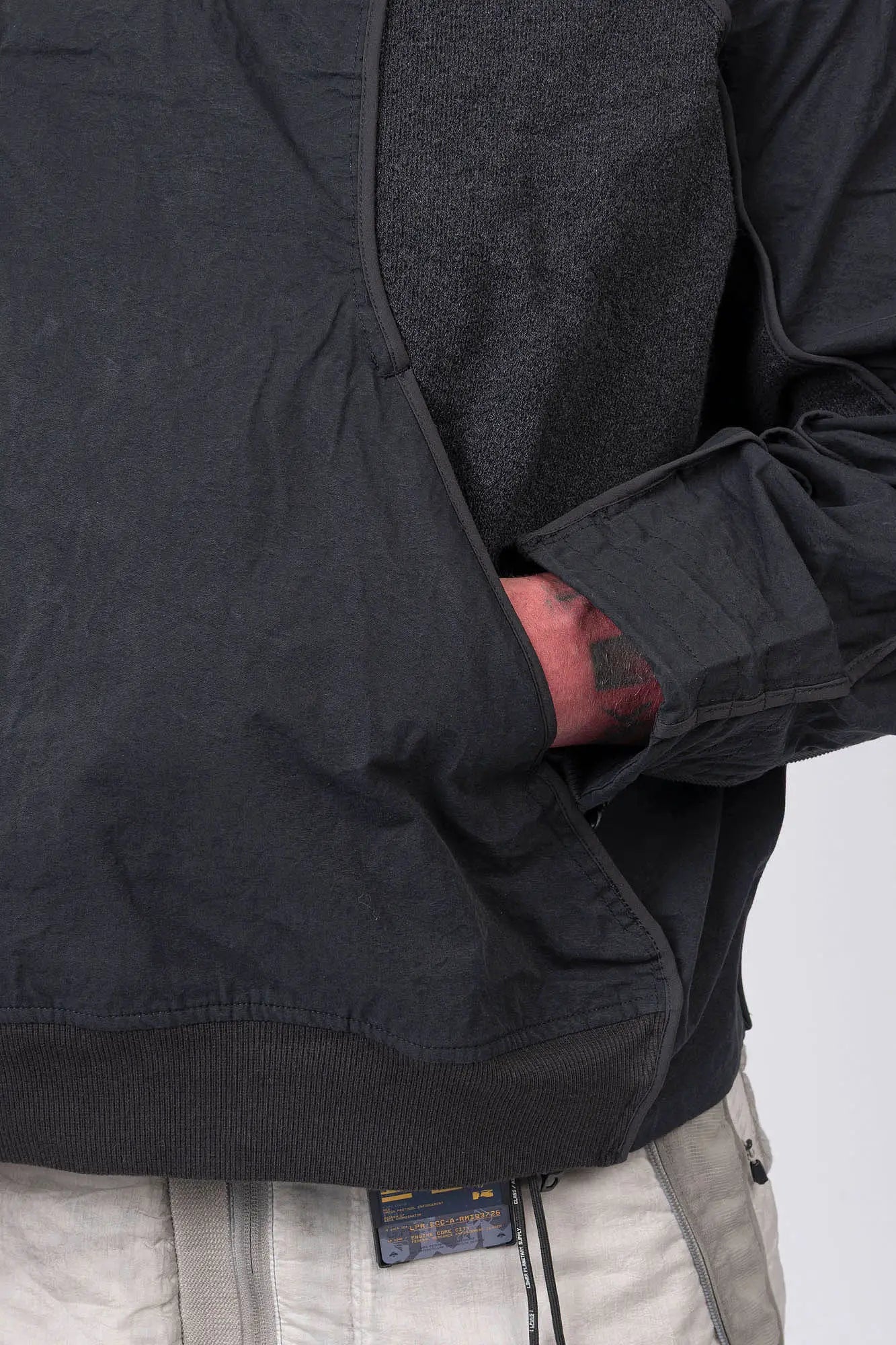 Hamcus, Mens Pullover, Matte Black, Dark Grey, Dark Gray, Half-Zip, Quarter-Zip, Long Sleeves, Mock Neck, Symmetric Panel Design, Ribbed Hem and Sleeve Cuffs, Side Pockets, Elastic Drawcord Adjustable Cuffs with Cordstoppers, Ribbed Neck, Back LP World Print, Left Hand in Pocket Close-up View. 