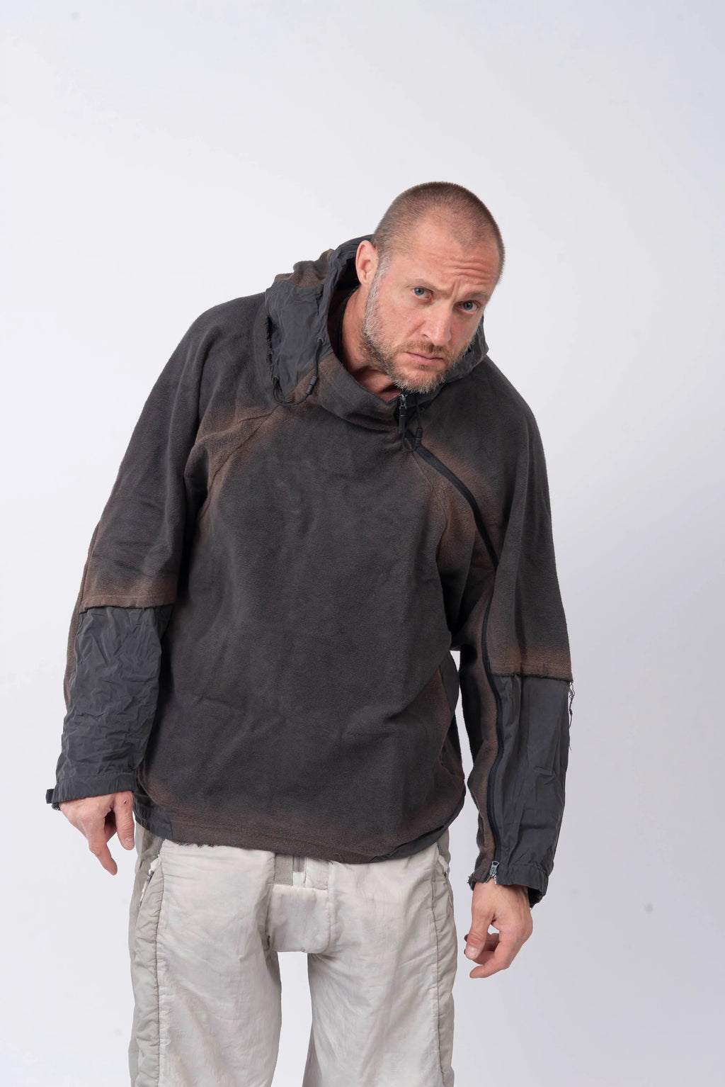 Hamcus, Mens Hoodie, Star-Scorched Black, Brown Details, Sun-Faded, Multiple Ventilation Zipper Openings, Hooded, Adjustable Drawcord Hood, Multi-Fabric Blend, LP World, Lower Planetary Universe, Tattoos, Raw-Cut Details, Elasticated Cuffs, Front View Leaned Over Looking directly at the Camera. 