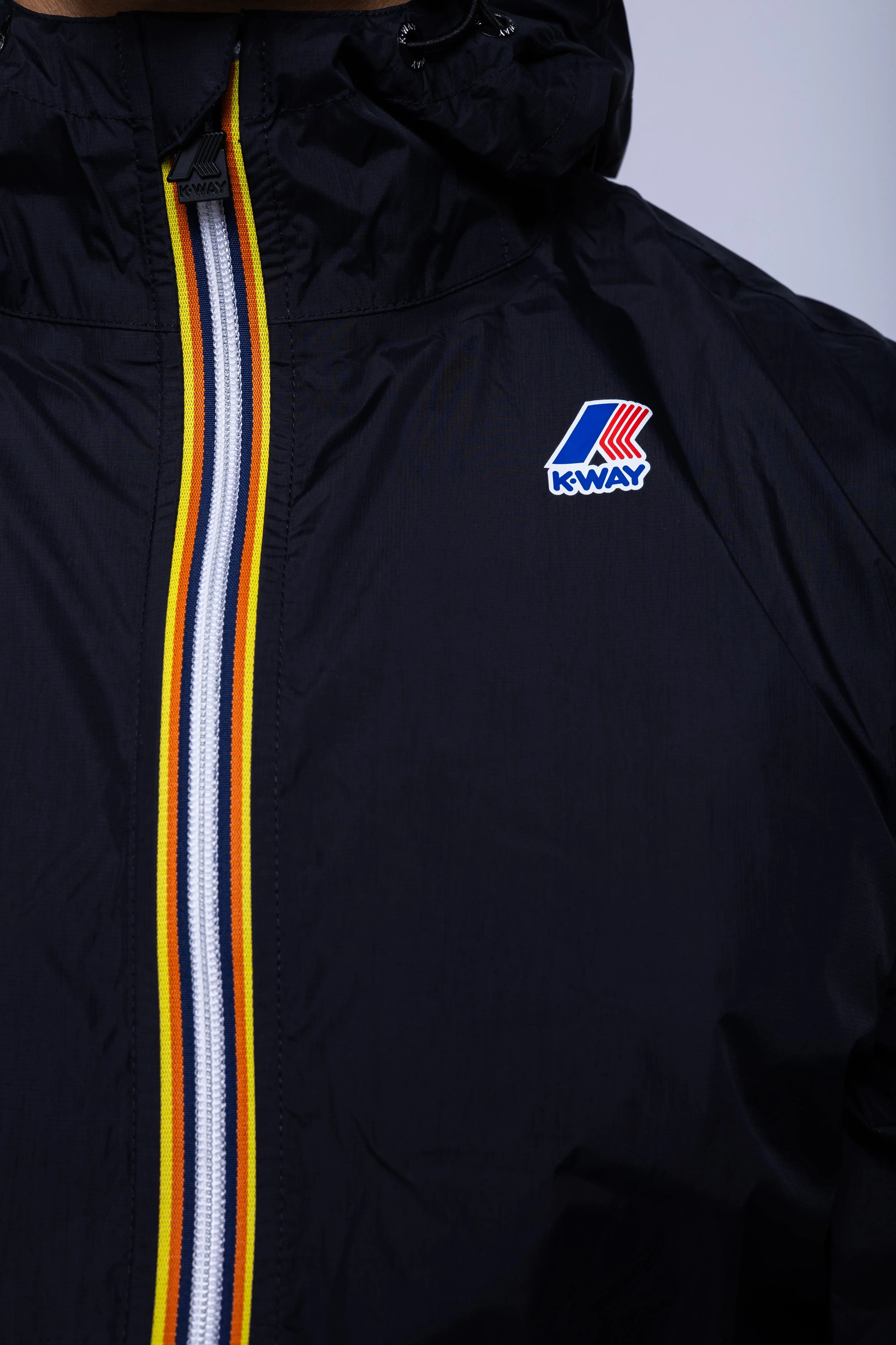 K-Way, Mens Jacket, Black, Unisex, Full-Zip, Chest Logo, Branded Zippers, Long Sleeves, Waterproof 10000 mm water column, Windproof 10000 g/sqm/24h, Heat Taped Seams, Elasticated Cuffs and Hem, Hooded, Drawcord, Signature Zip Tape, Zip and Chest Logo Close-up. 