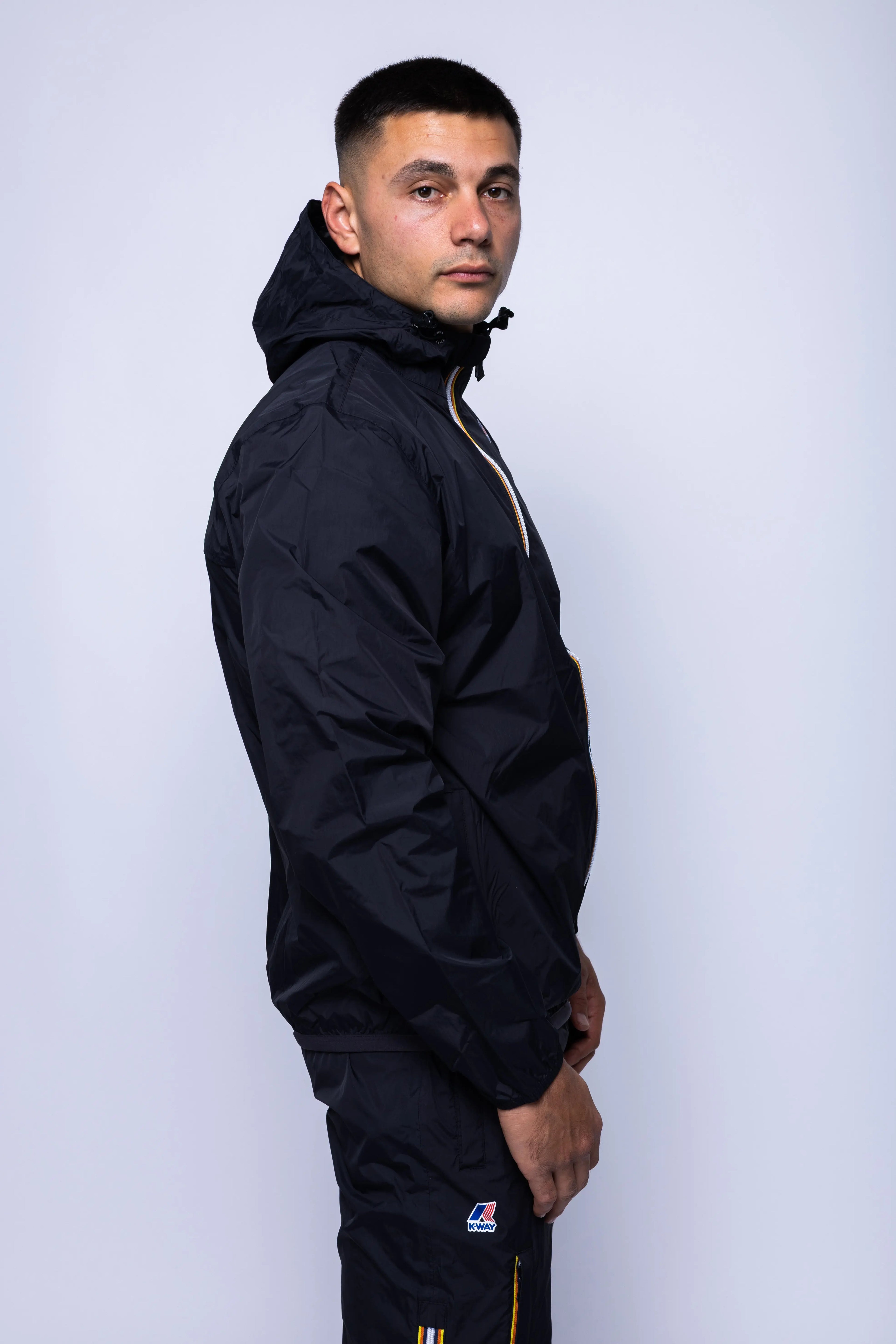 K-Way, Mens Jacket, Black, Unisex, Full-Zip, Chest Logo, Branded Zippers, Long Sleeves, Waterproof 10000 mm water column, Windproof 10000 g/sqm/24h, Heat Taped Seams, Elasticated Cuffs and Hem, Hooded, Drawcord, Side VIew. 