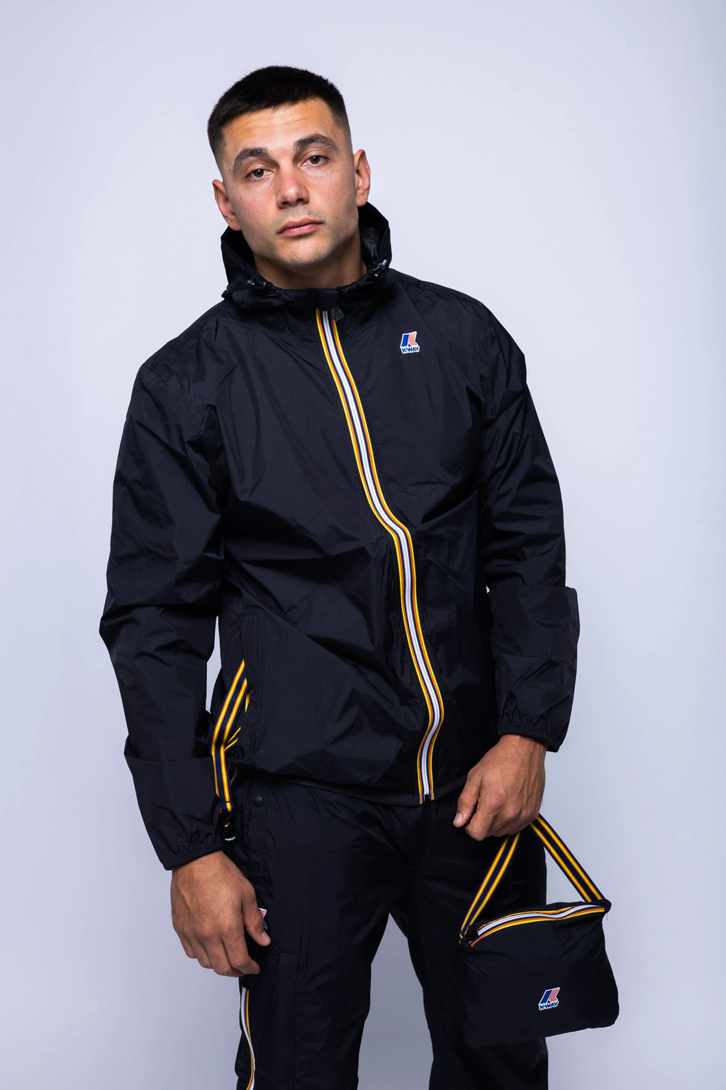 K-Way, Mens Jacket, Black, Unisex, Full-Zip, Chest Logo, Branded Zippers, Long Sleeves, Waterproof 10000 mm water column, Windproof 10000 g/sqm/24h, Heat Taped Seams, Elasticated Cuffs and Hem, Hooded, Drawcord, Front Portrait in-motion. 