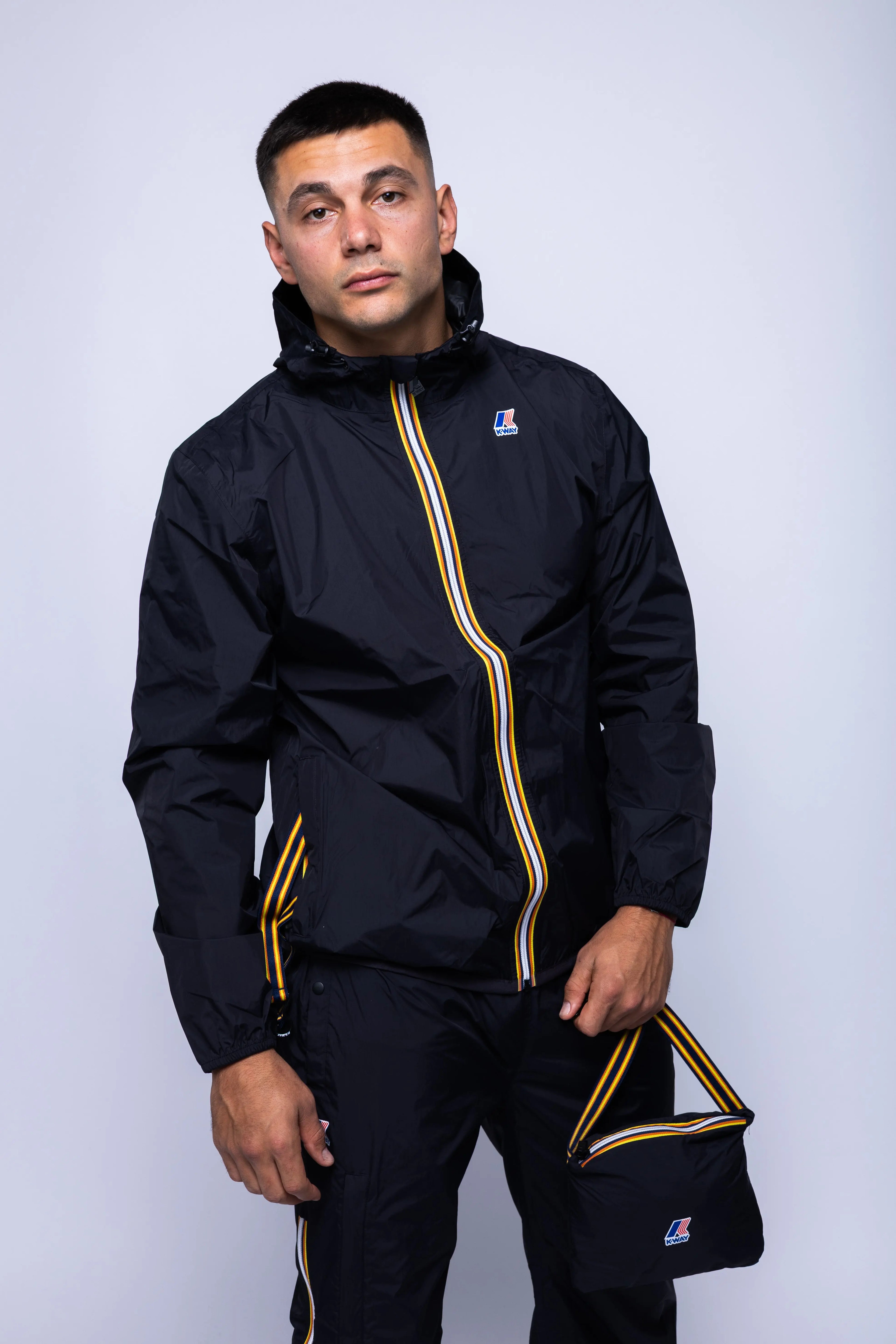 K-Way, Mens Jacket, Black, Unisex, Full-Zip, Chest Logo, Branded Zippers, Long Sleeves, Waterproof 10000 mm water column, Windproof 10000 g/sqm/24h, Heat Taped Seams, Elasticated Cuffs and Hem, Hooded, Drawcord, Front Portrait in-motion. 
