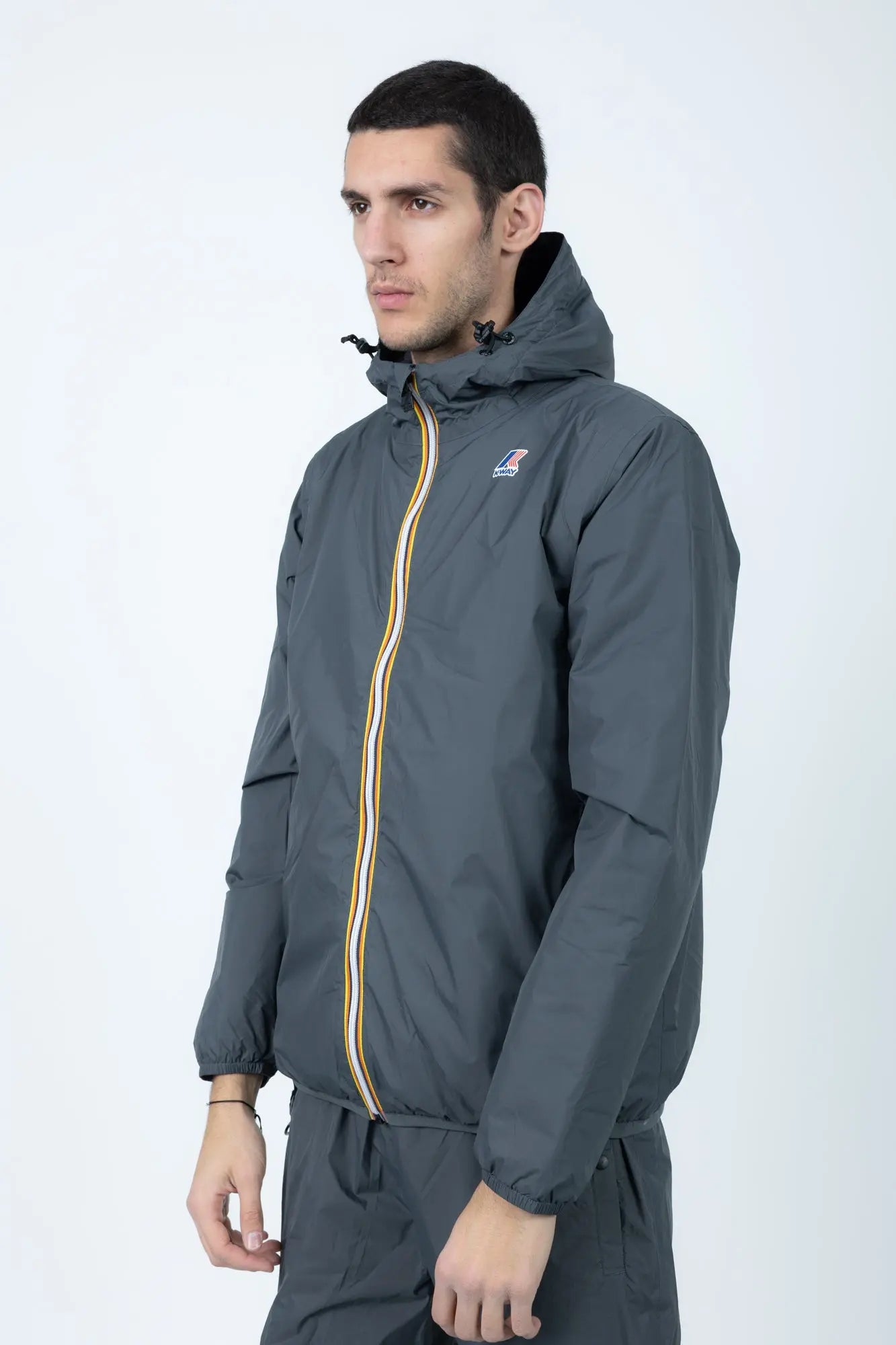 K-Way, Mens Jacket, Grey Shadow DK, Full-Zip, Hooded, Side Pockets, Branded Zippers, Packable, Unisex, Long Sleeves, Waterproof 10000 mm water column, Windproof, Breathable, Water-Repellent, Elasticated Cuffs and Hem, Breathability: 10000 g/sqm/24h, Front Portrait 3/4 View. 