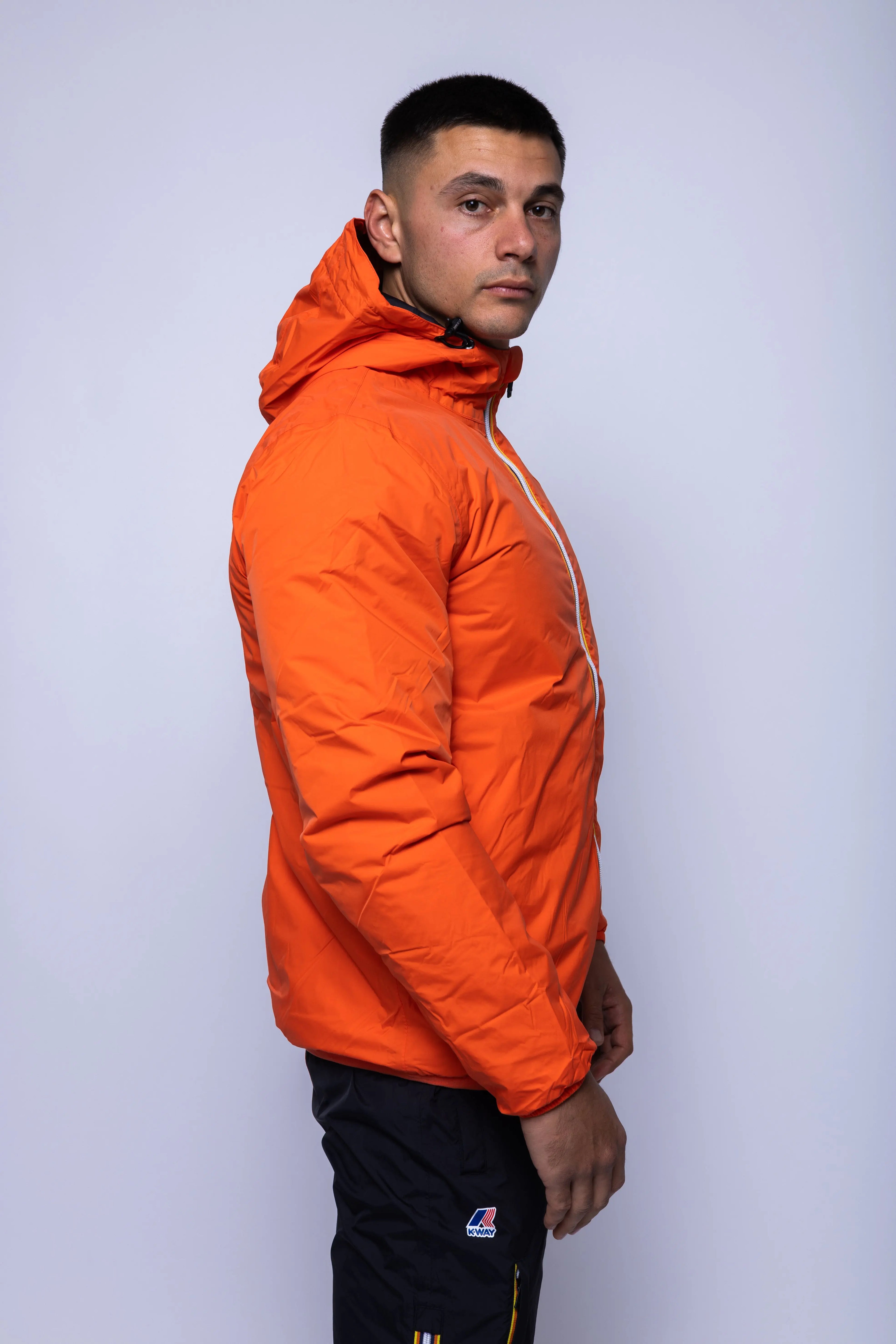 K-Way, Mens Jacket, Orange Fiesta, Full-Zip, Hooded, Side Pockets, Branded Zippers, Packable, Unisex, Long Sleeves, Waterproof 10000 mm water column, Windproof, Breathable, Water-Repellent, Elasticated Cuffs and Hem, Breathability: 10000 g/sqm/24h, Side View. 
