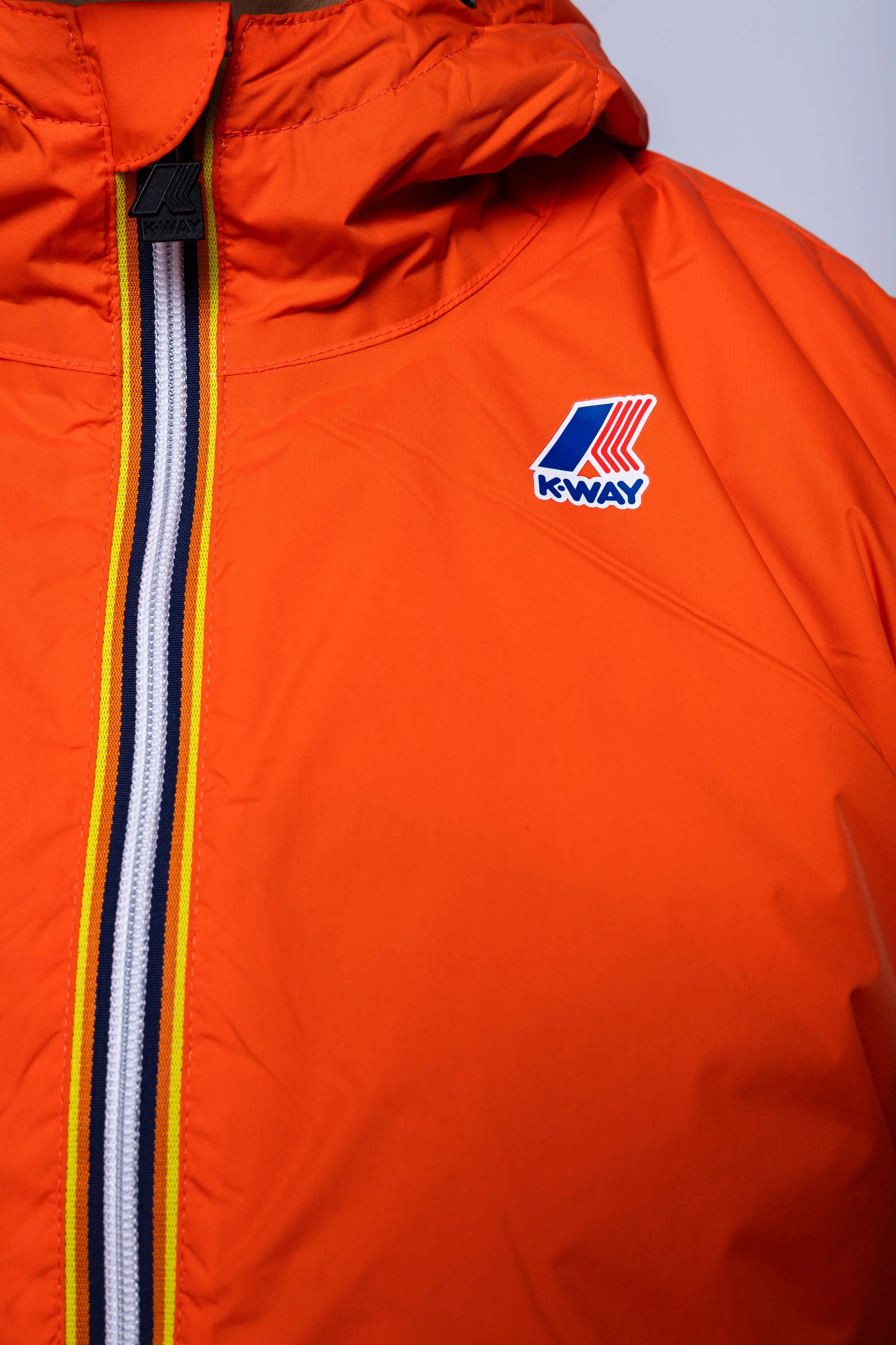 K-Way, Mens Jacket, Orange Fiesta, Full-Zip, Hooded, Side Pockets, Branded Zippers, Packable, Unisex, Long Sleeves, Waterproof 10000 mm water column, Windproof, Breathable, Water-Repellent, Elasticated Cuffs and Hem, Breathability: 10000 g/sqm/24h, Chest Logo Close-up. 