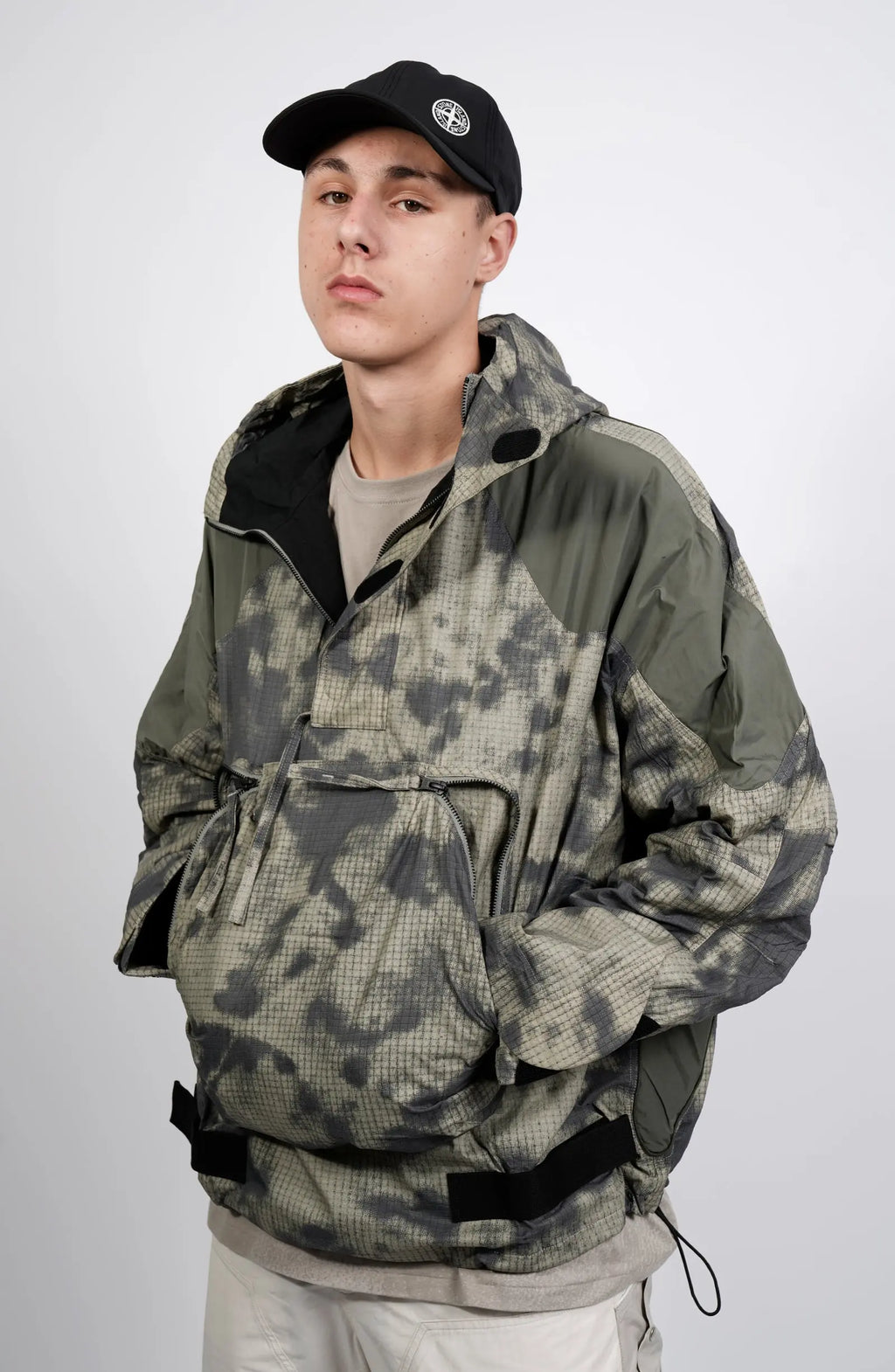 Nilmance, Mens Jacket, Green Camo, Elastic Concealed Drawcord Hood and Hem, Velcro Adjustable Cuffs and Hood, Large Front Zip Pocket, YKK Zippers, Ripstop Nylon, Water-repellent treated, Front 3/4 Portrait View. 