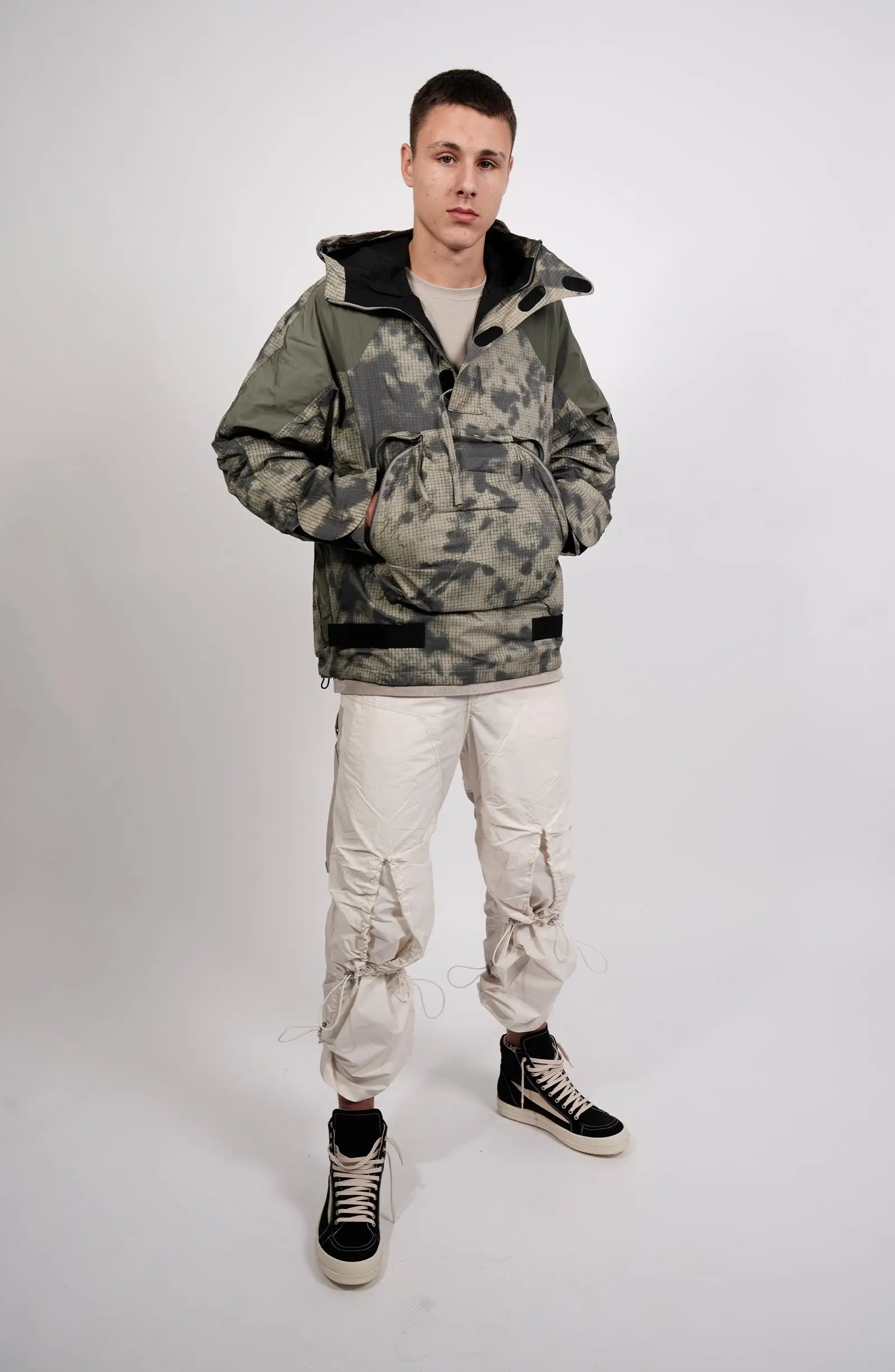 Nilmance, Mens Jacket, Green Camo, Elastic Concealed Drawcord Hood and Hem, Velcro Adjustable Cuffs and Hood, Large Front Zip Pocket, YKK Zippers, Ripstop Nylon, Water-repellent treated, Full Body Front 3/4 View Hands in Pockets. 