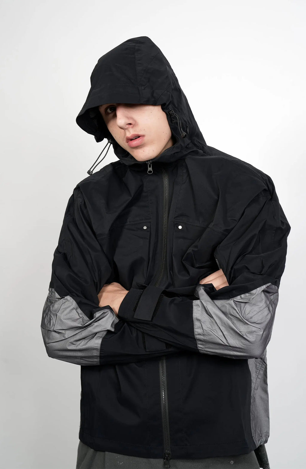 Nilmance, Mens Jacket, Black and Grey, Drawcord Hooded, Velcro, Full Zip, Vislon YKK Zippers, Velcro Adjustsable Cuffs, Bellows Pockets, Side Pockets, Elastic Drawcord, Silver Tone Details, Front Portrait Crossed Hands. 