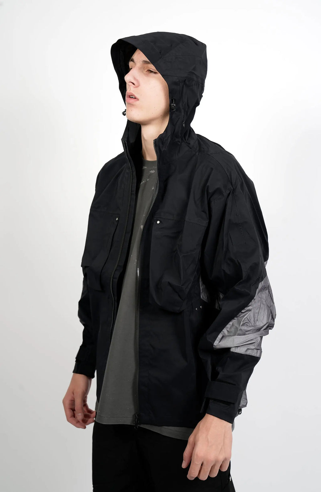 Nilmance, Mens Jacket, Black and Grey, Drawcord Hooded, Velcro, Full Zip, Vislon YKK Zippers, Velcro Adjustsable Cuffs, Bellows Pockets, Side Pockets, Elastic Drawcord, Silver Tone Details, Front Portrait 3/4 View. 