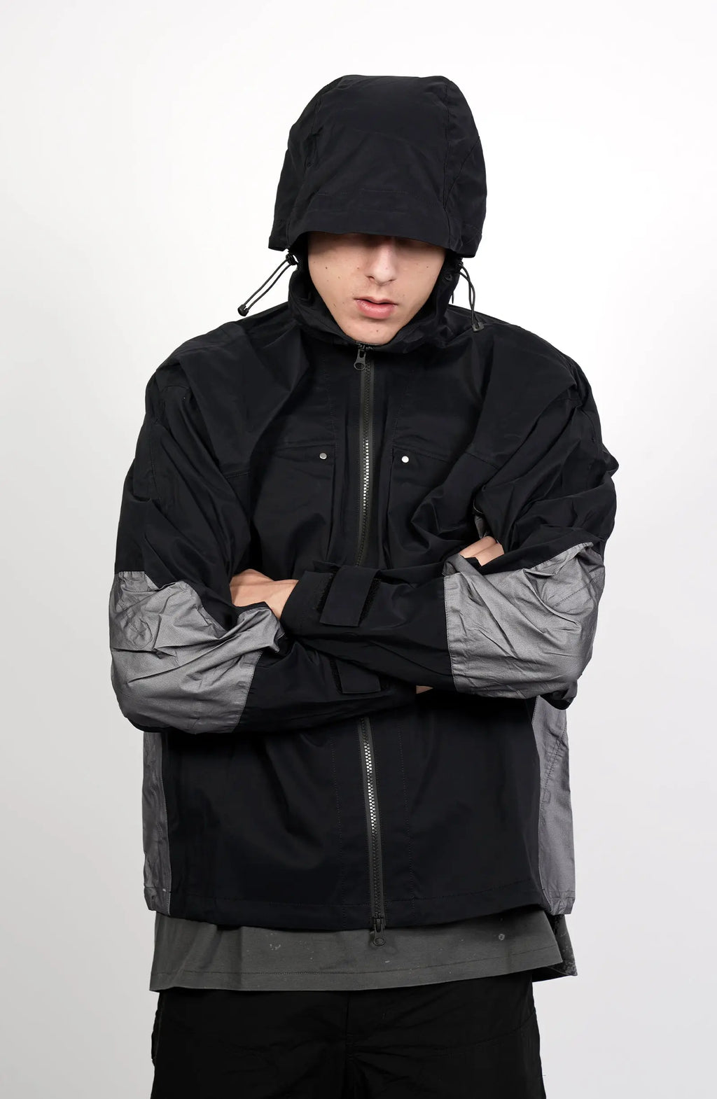 Nilmance, Mens Jacket, Black and Grey, Drawcord Hooded, Velcro, Full Zip, Vislon YKK Zippers, Velcro Adjustsable Cuffs, Bellows Pockets, Side Pockets, Elastic Drawcord, Silver Tone Details, Front View Crossed Hands Hooded. 