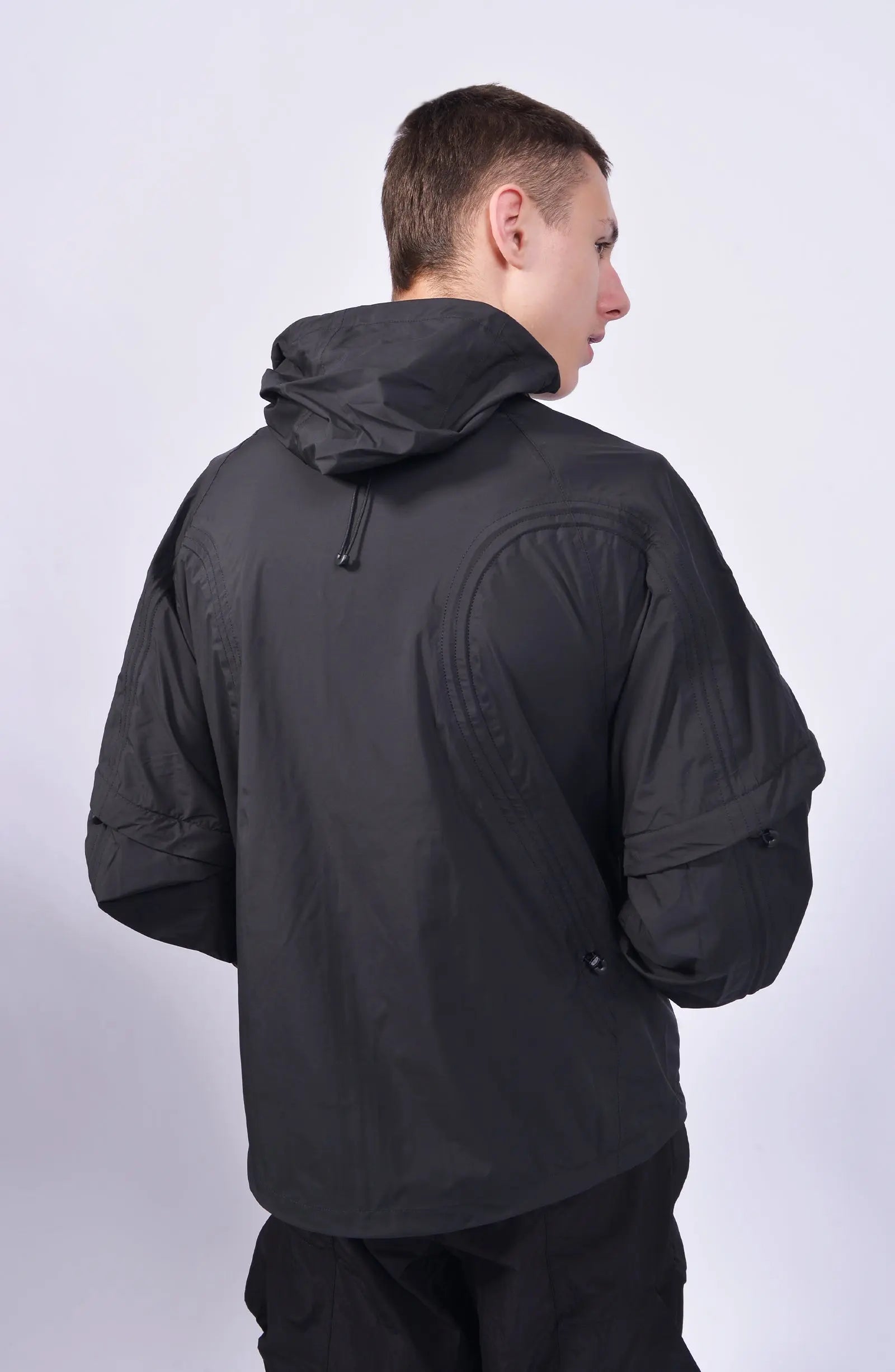 Nilmance, Mens Jacket, Black, Waterproof 10k, Windproof, Water-Repellent, Full-Zip, Zip Pockets, Side Pockets, Hidden Pockets, Detachable Sleeves, Velcro Adjustable Cuffs, Drawcord Hood, Cinch Hood, Zip Ventilation Openings, Back 3/4 Portrait View Looking Sideways. 