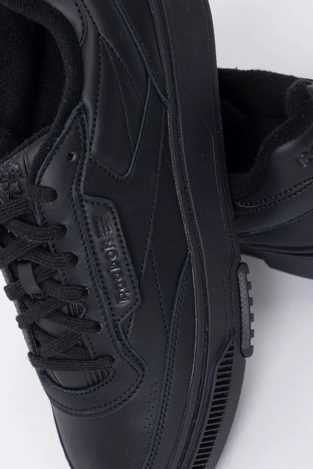 Reebok, Mens Sneakers, Black, Full Leather, Low-Cut Design, Rubber Outsole, Cushioned EVA Midsole, Reebok Club C LTD SS26, Leather U.K. Details, Wimbledon Sneaker, Tennis Court, Grass, Racket, Wilson, Head, Top-Down Details Close-up View. 