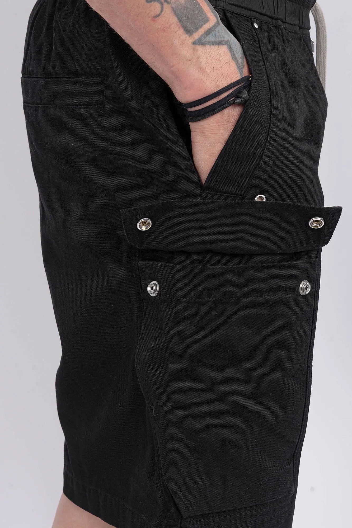Rick Owens,Mens Shorts,Knee Lenght,Low Crotch,Wide Leg,Elastic Waistband With Drawstrings,Bela Exposed Center Zipper With Two Snap Detail,Two Side Beveled Cargo Pockets With Concealed Snaps And Topstitching , Two Rear Welt Pockets With Concealed Snaps And Topstitching, Lightweight Wash Milk Denim,Black And Natural 8OZ Denim,Dyed,Waxed By Hand,Side View, Detailed Photo Of The Cargo Pocket.
