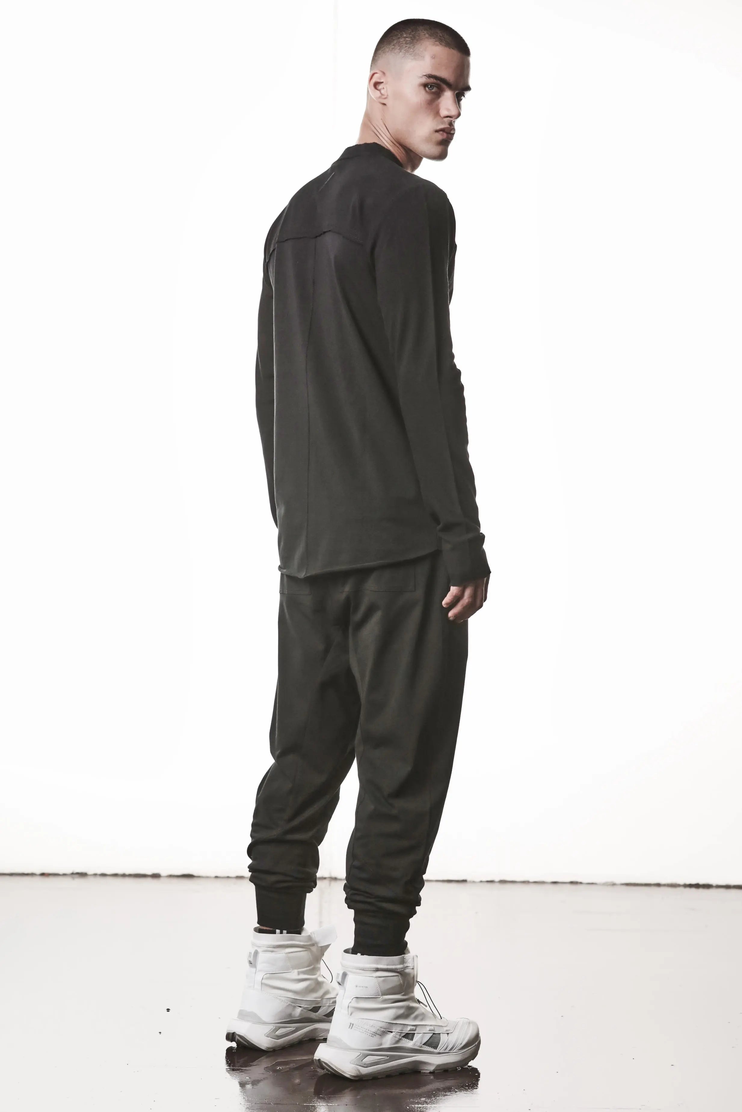 Thom Krom, Mens Shirt, Black, Stretch Sleeves, Exposed Seams, Stitched Logo, Thom/Krom, The Night is your friend, my love, Long Sleeves, Ribbed Collar, Full Body Back 3/4 View. 