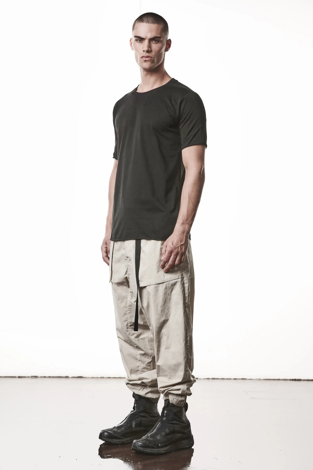 Thom Krom, Mens T-Shirt, Black, Raw-Cut Hem, Elastic Neck, 100% Cotton, Short Sleeves, Crewneck, Round Neck, White Cross Seams, Back Seams, Embroidered Logo, Full Body 3/4 Front View. 