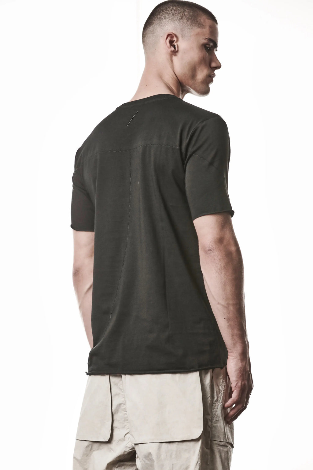 Thom Krom, Mens T-Shirt, Black, Raw-Cut Hem, Elastic Neck, 100% Cotton, Short Sleeves, Crewneck, Round Neck, White Cross Seams, Back Seams, Embroidered Logo, Back Portrait 3/4 View. 