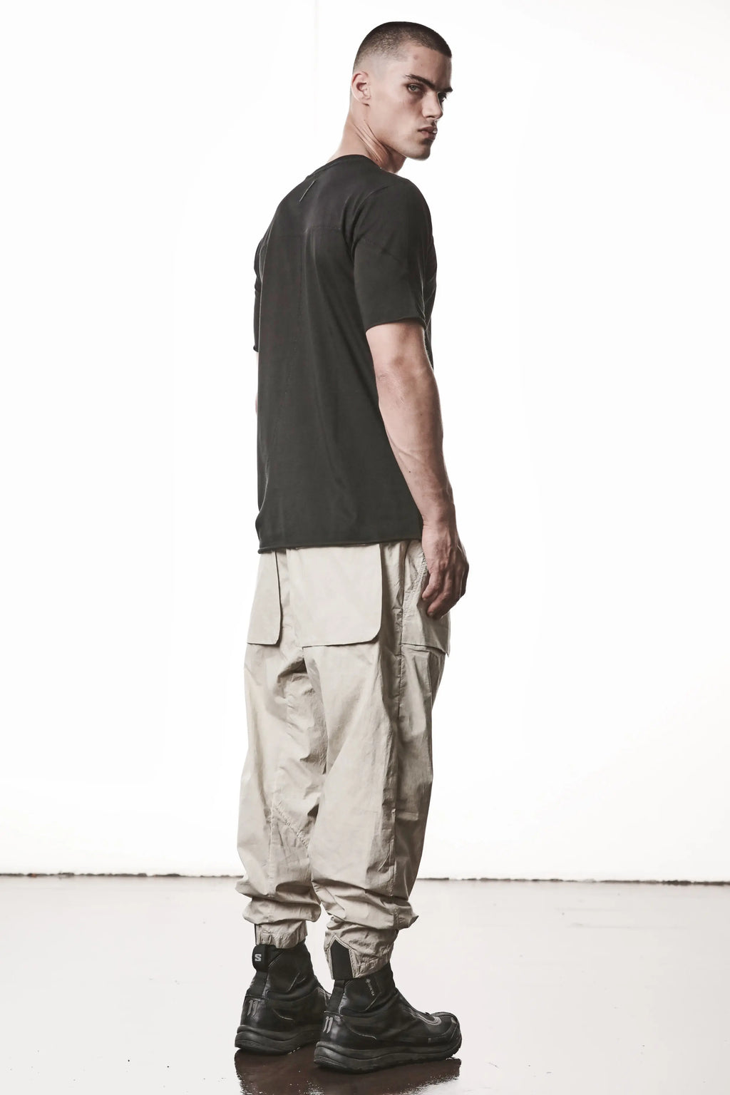 Thom Krom, Mens T-Shirt, Black, Raw-Cut Hem, Elastic Neck, 100% Cotton, Short Sleeves, Crewneck, Round Neck, White Cross Seams, Back Seams, Embroidered Logo, Full Body Back 3/4 View. 