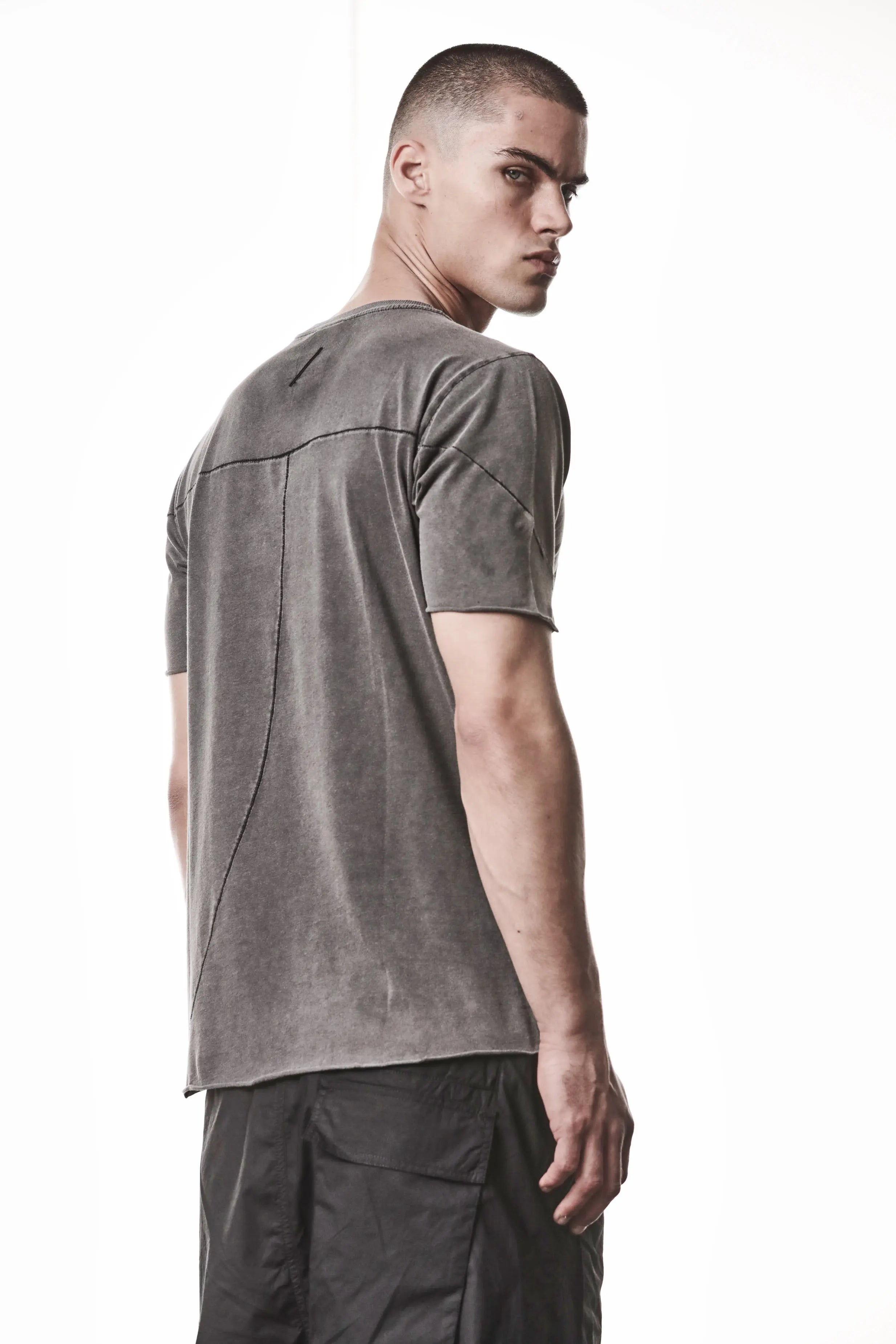 Thom Krom, Mens T-Shirt, Dark Used Grey, Raw-Cut Hem, Elastic Neck, 100% Cotton, Short Sleeves, Crewneck, Round Neck, Dark Seams, Back Seams, Embroidered Logo, Back 3/4 View. 