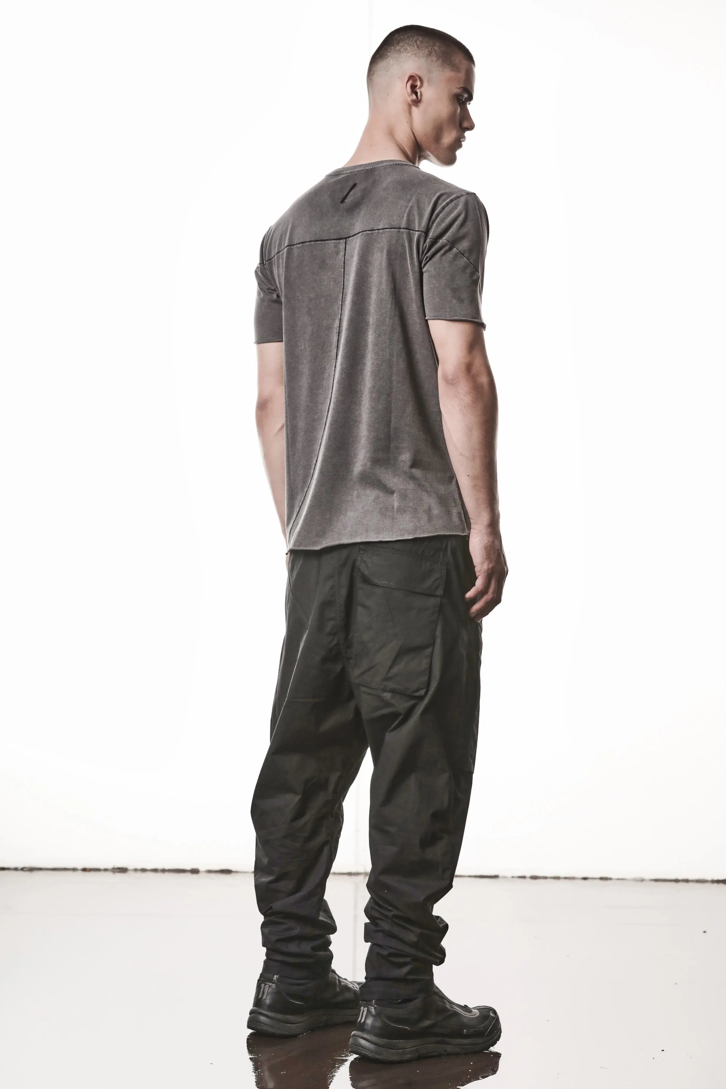 Thom Krom, Mens T-Shirt, Dark Used Grey, Raw-Cut Hem, Elastic Neck, 100% Cotton, Short Sleeves, Crewneck, Round Neck, Dark Seams, Back Seams, Embroidered Logo, Full Body Back 3/4 View.
