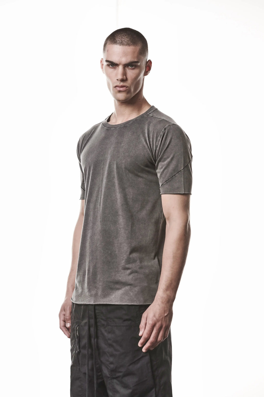 Thom Krom, Mens T-Shirt, Dark Used Grey, Raw-Cut Hem, Elastic Neck, 100% Cotton, Short Sleeves, Crewneck, Round Neck, Dark Seams, Back Seams, Embroidered Logo, Front Portrait 3/4 View. 