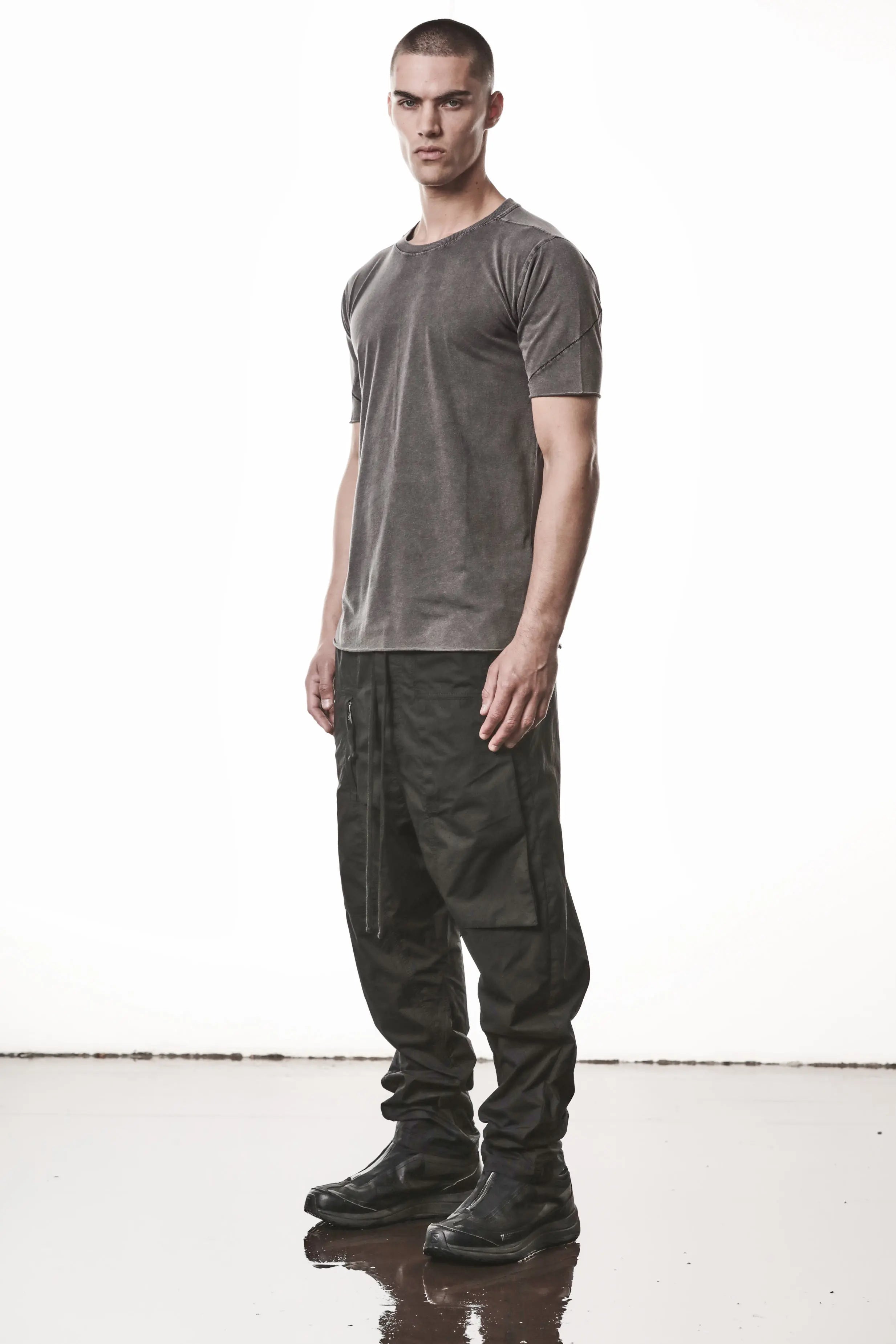 Thom Krom, Mens T-Shirt, Dark Used Grey, Raw-Cut Hem, Elastic Neck, 100% Cotton, Short Sleeves, Crewneck, Round Neck, Dark Seams, Back Seams, Embroidered Logo, Full Body 3/4 Front View. 