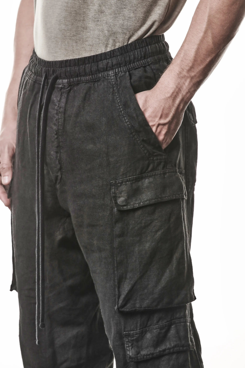 Thom Krom, Mens Pants, Black, Linen, Elasticated Waistband and Cuffs, Low-Crotch Trousers, Cargo Details, Black Drawstring, Side Pockets, Back Pockets, Front 3/4 View Cargo Details and Hand in Pocket. 