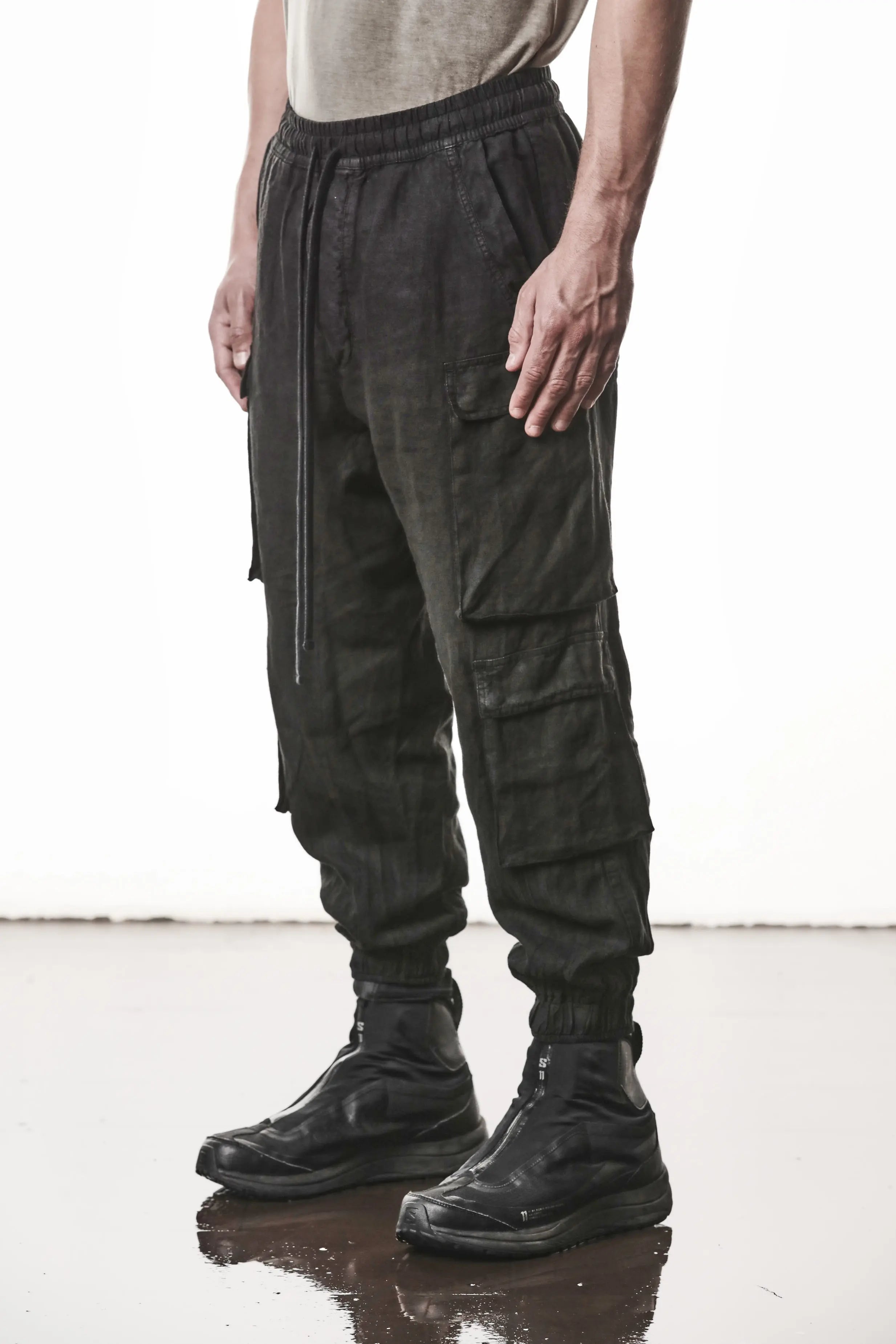 Thom Krom, Mens Pants, Black, Linen, Elasticated Waistband and Cuffs, Low-Crotch Trousers, Cargo Details, Black Drawstring, Side Pockets, Back Pockets, Front 3/4 View. 