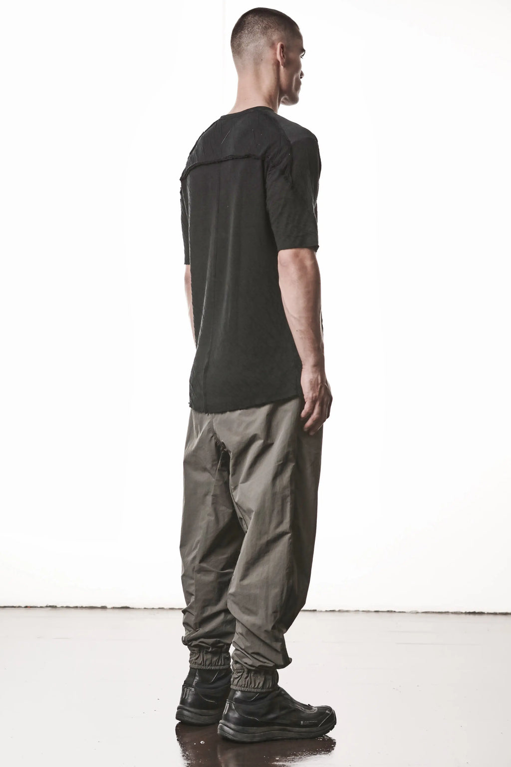 Thom Krom T-Shirt ,Mens T-Shirt,Black Cotton, Raw Cut Hem , Raw Cut Sleeves ,Round Crewneck , Slim Fit,Standart Lenght,Signature Front Level  Shoulders Seams,Lightweight Crashed Bonded Cotton,Backside Stiching Line,Logo Embroidery On The Back, Whole Body Side Angle Photo