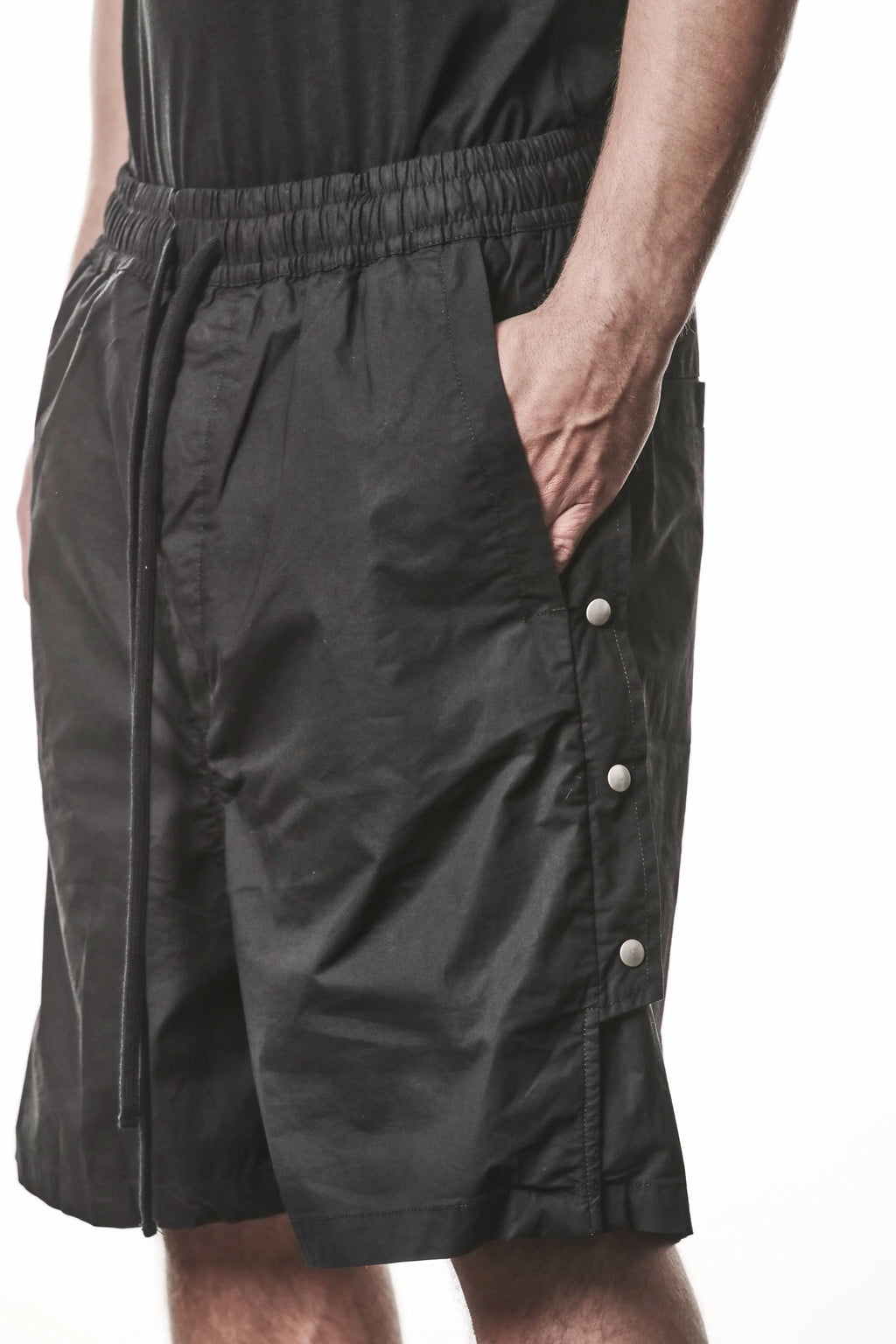 Thom Krom, Mens Shorts, Black, Over the Knee, Elasticated Waistband, Black Drawstring, Cargo Pockets, Side Pockets, Wide-fit, Drop-crotch, Front 3/4 View Hand in Pocket. 