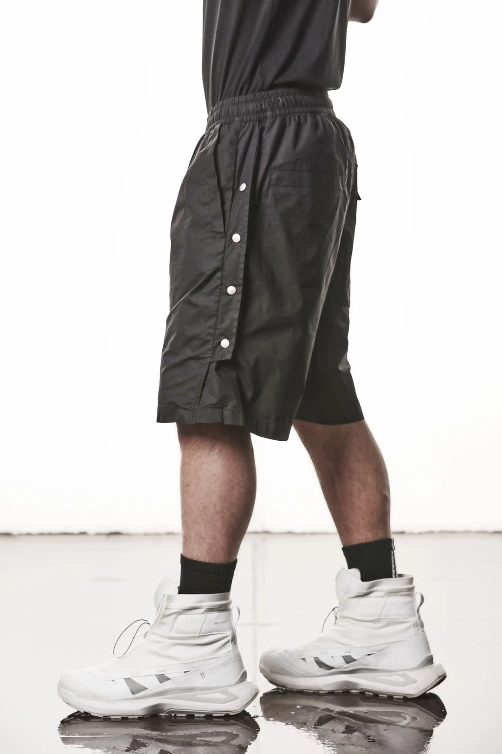 Thom Krom, Mens Shorts, Black, Over the Knee, Elasticated Waistband, Black Drawstring, Cargo Pockets, Side Pockets, Wide-fit, Drop-crotch, Side View Step Forward. 