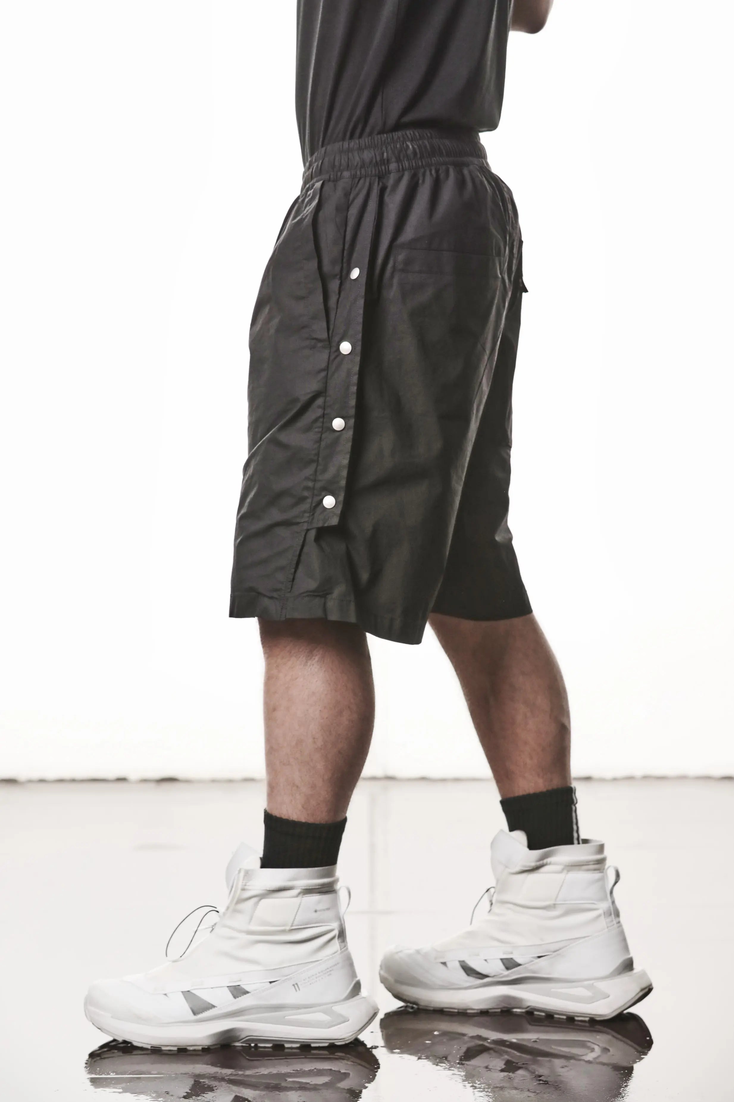 Thom Krom, Mens Shorts, Black, Over the Knee, Elasticated Waistband, Black Drawstring, Cargo Pockets, Side Pockets, Wide-fit, Drop-crotch, Side View Step Forward. 