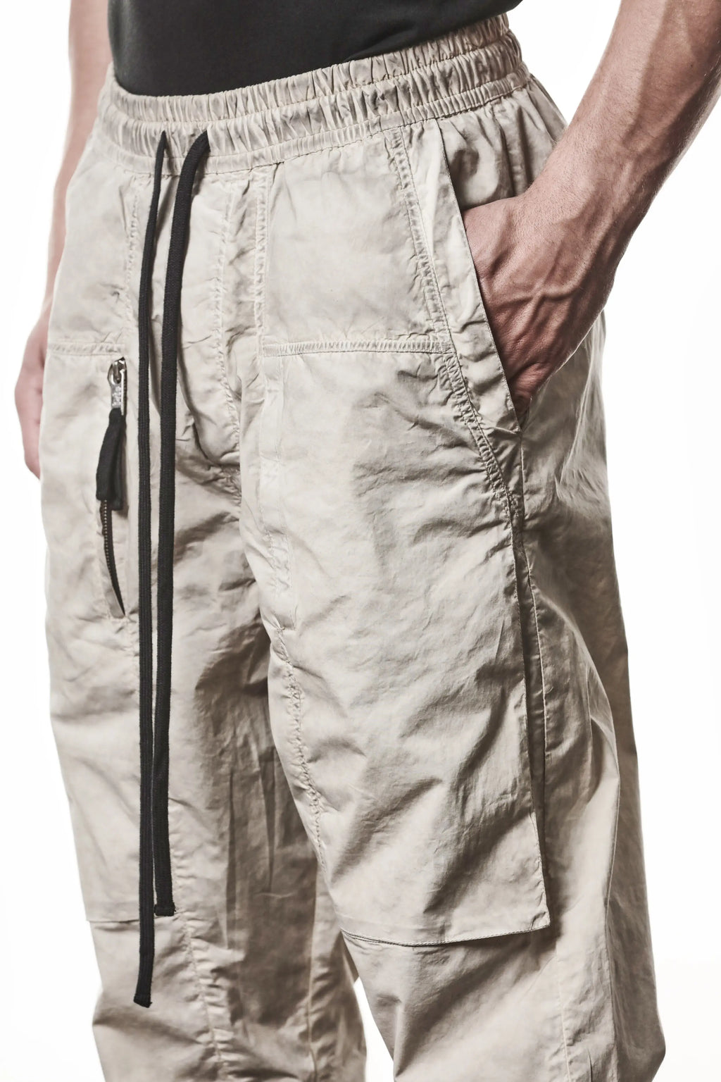 Thom Krom, Mens Pants, Vegetal Stone, Beige, Oversized, Wide-fit, Loose-fit, Large Front Pockets, Side Pockets, Back Pockets, Elasticated Waistband, Black Drawstring, Zip Pockets, YKK Zippers, Wide Ankles, Close-up Front 3/4 View Hand in Pocket. 