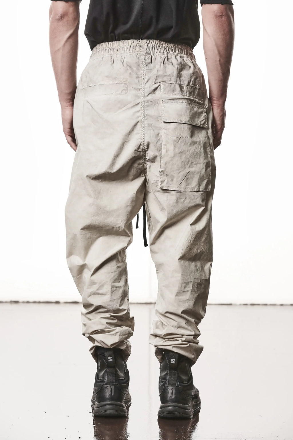 Thom Krom, Mens Pants, Vegetal Stone, Beige, Oversized, Wide-fit, Loose-fit, Large Front Pockets, Side Pockets, Back Pockets, Elasticated Waistband, Black Drawstring, Zip Pockets, YKK Zippers, Wide Ankles, Back View. 