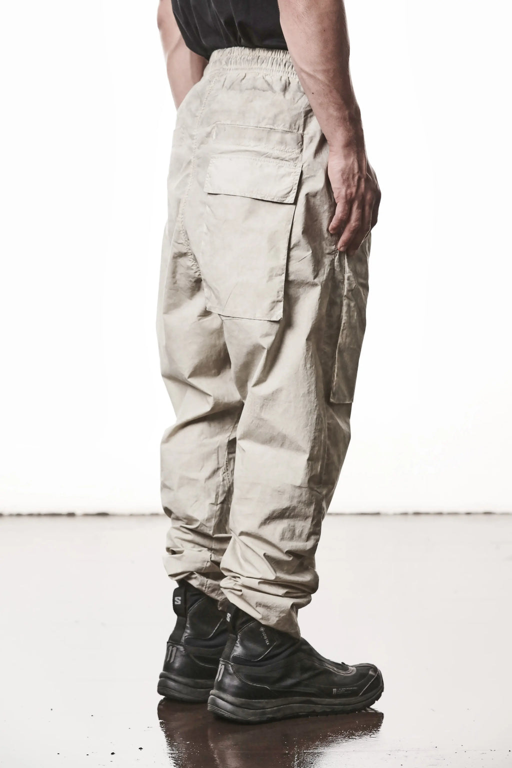 Thom Krom, Mens Pants, Vegetal Stone, Beige, Oversized, Wide-fit, Loose-fit, Large Front Pockets, Side Pockets, Back Pockets, Elasticated Waistband, Black Drawstring, Zip Pockets, YKK Zippers, Wide Ankles, Back 3/4 View. 