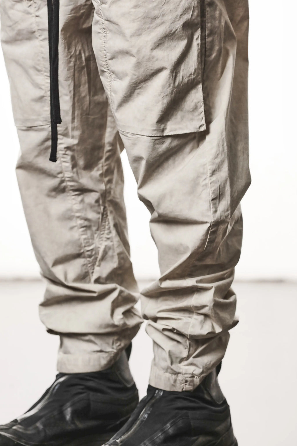 Thom Krom, Mens Pants, Vegetal Stone, Beige, Oversized, Wide-fit, Loose-fit, Large Front Pockets, Side Pockets, Back Pockets, Elasticated Waistband, Black Drawstring, Zip Pockets, YKK Zippers, Wide Ankles, Front 3/4 Leg Fit Close-up. 