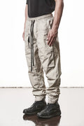 Thom Krom, Mens Pants, Vegetal Stone, Beige, Oversized, Wide-fit, Loose-fit, Large Front Pockets, Side Pockets, Back Pockets, Elasticated Waistband, Black Drawstring, Zip Pockets, YKK Zippers, Wide Ankles, Front 3/4 View. 