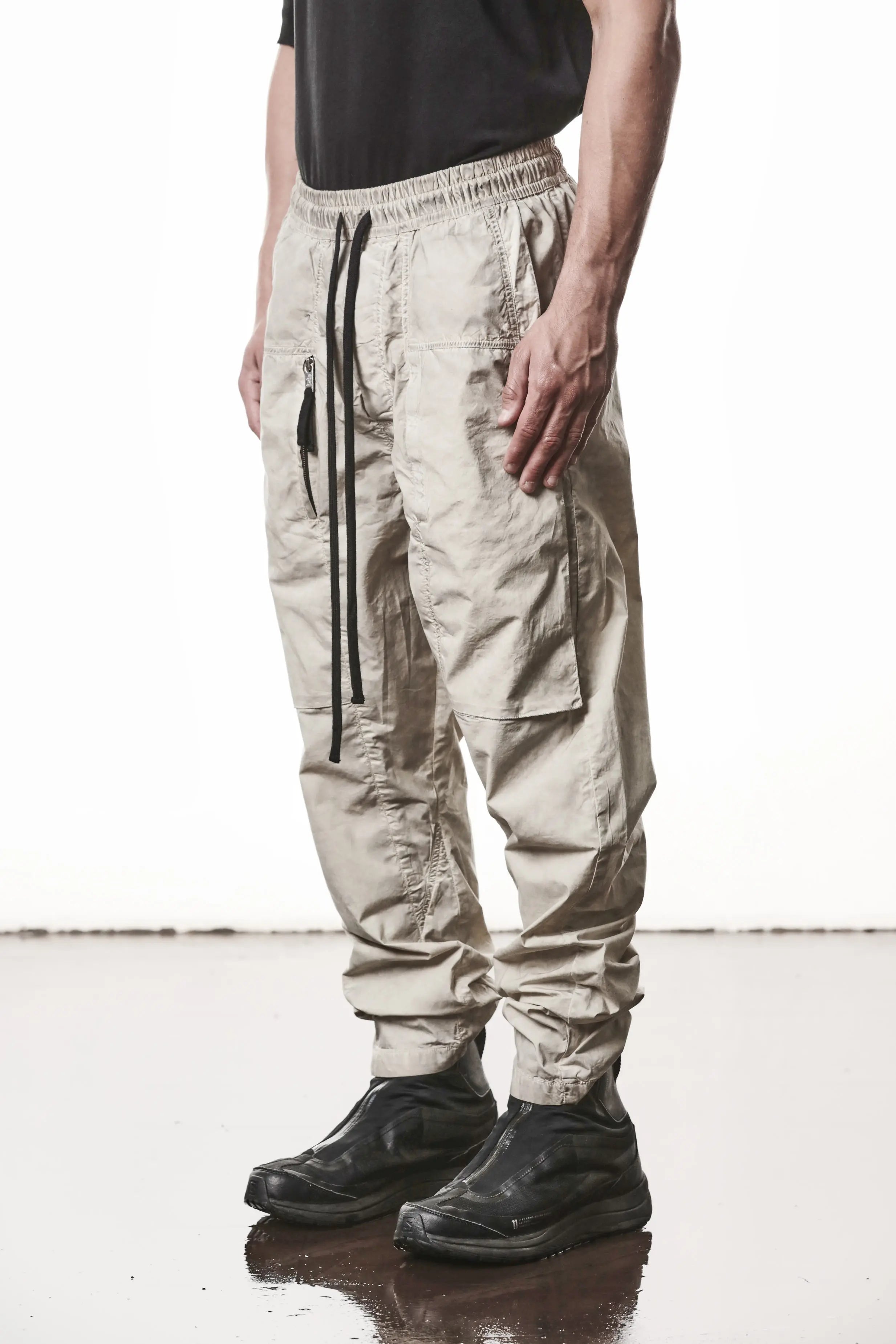 Thom Krom, Mens Pants, Vegetal Stone, Beige, Oversized, Wide-fit, Loose-fit, Large Front Pockets, Side Pockets, Back Pockets, Elasticated Waistband, Black Drawstring, Zip Pockets, YKK Zippers, Wide Ankles, Front 3/4 View. 